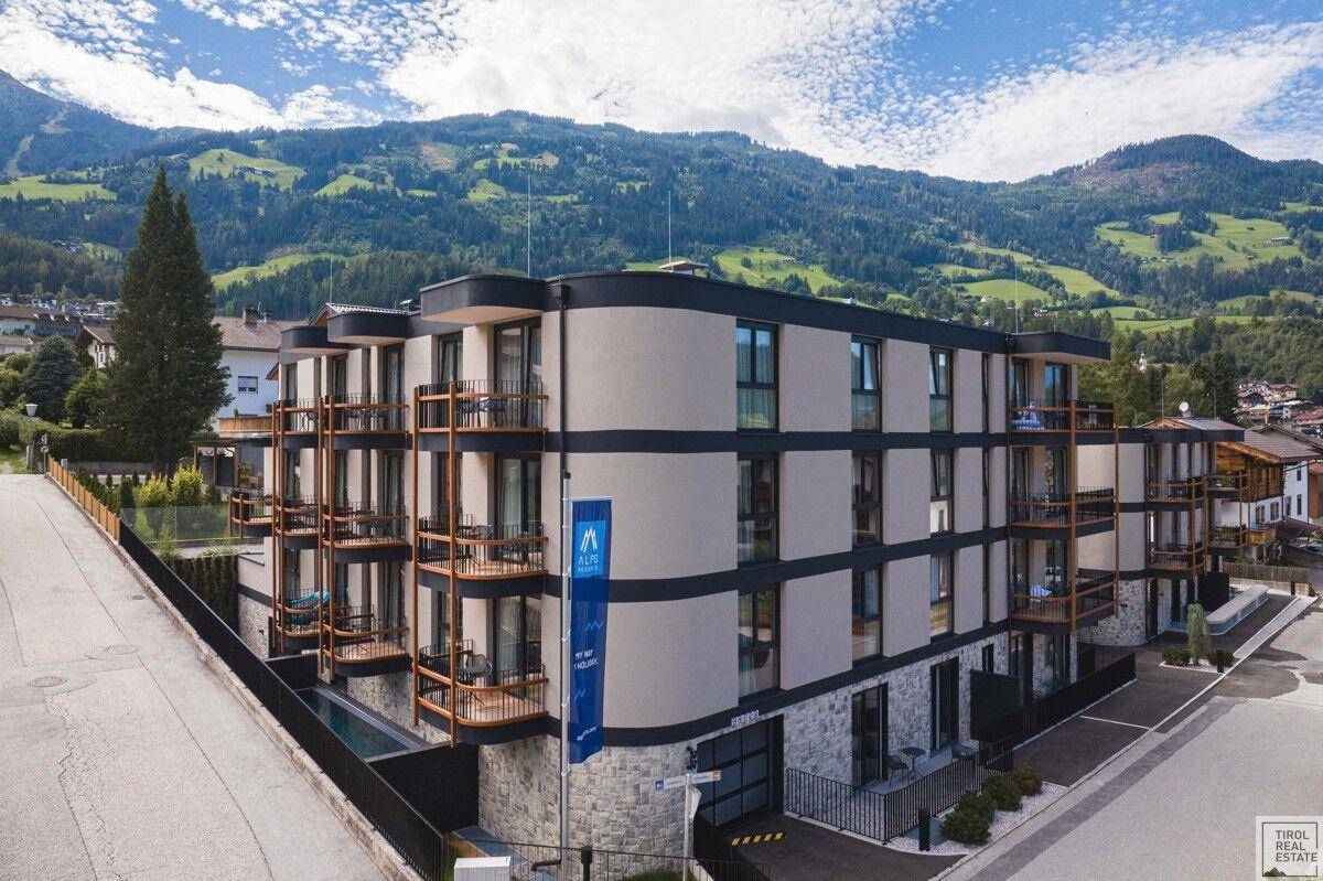 Modernes Apartmentgebäude in alpiner Umgebung mit Balkonen und Bergblick.