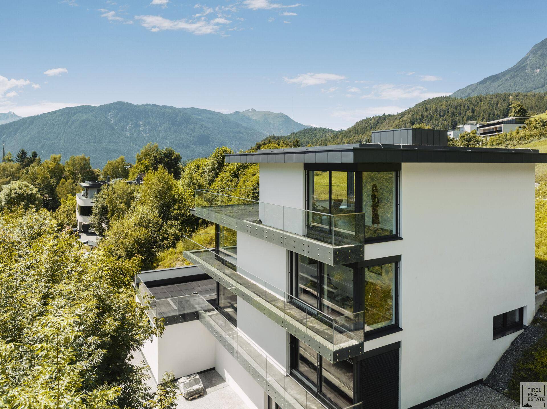 Seitenansicht der modernen Villa mit gestuften Terrassen und weitem Blick über die Berglandschaft.