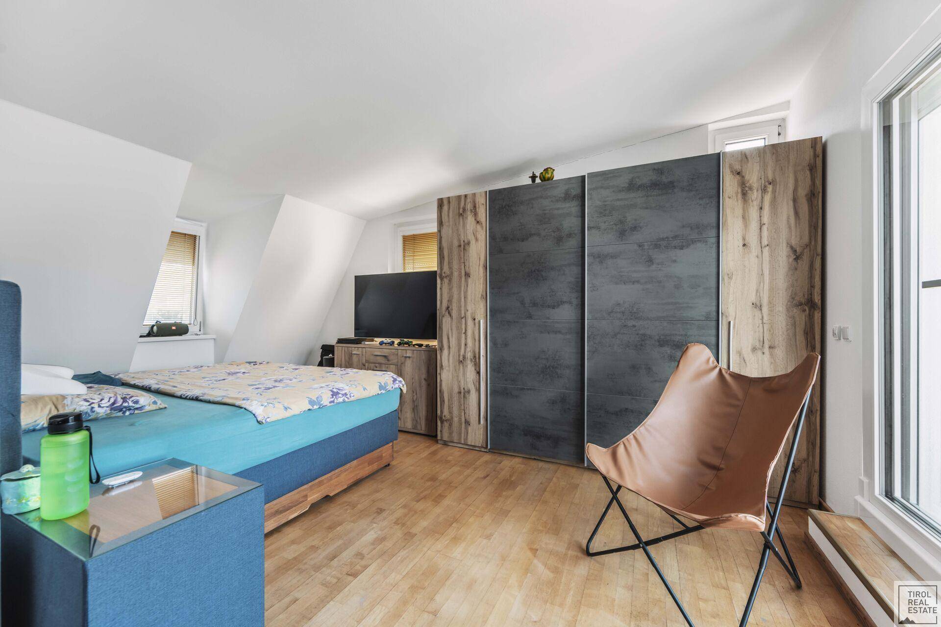 Dachgeschoss-Schlafzimmer mit Holzboden, Einbauschränken und viel Tageslicht.