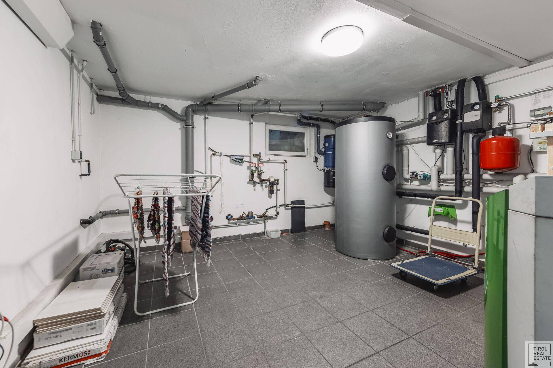 Technikraum im Untergeschoss mit Heizungsanlage, Warmwasserspeicher und Wäscheständer.