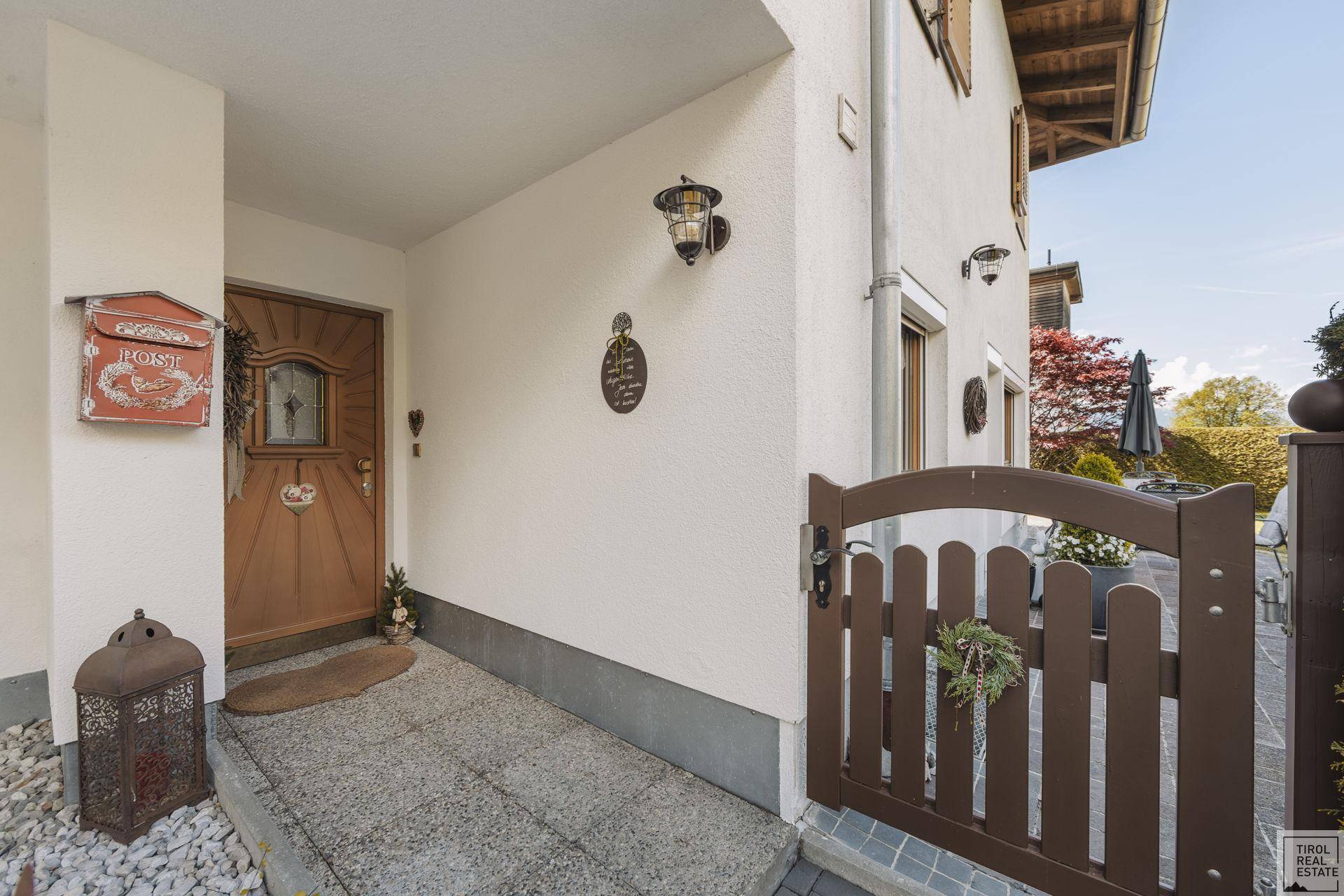 Eingangsbereich des Hauses mit Holztür, rustikalem Briefkasten und einem kleinen Holztor.