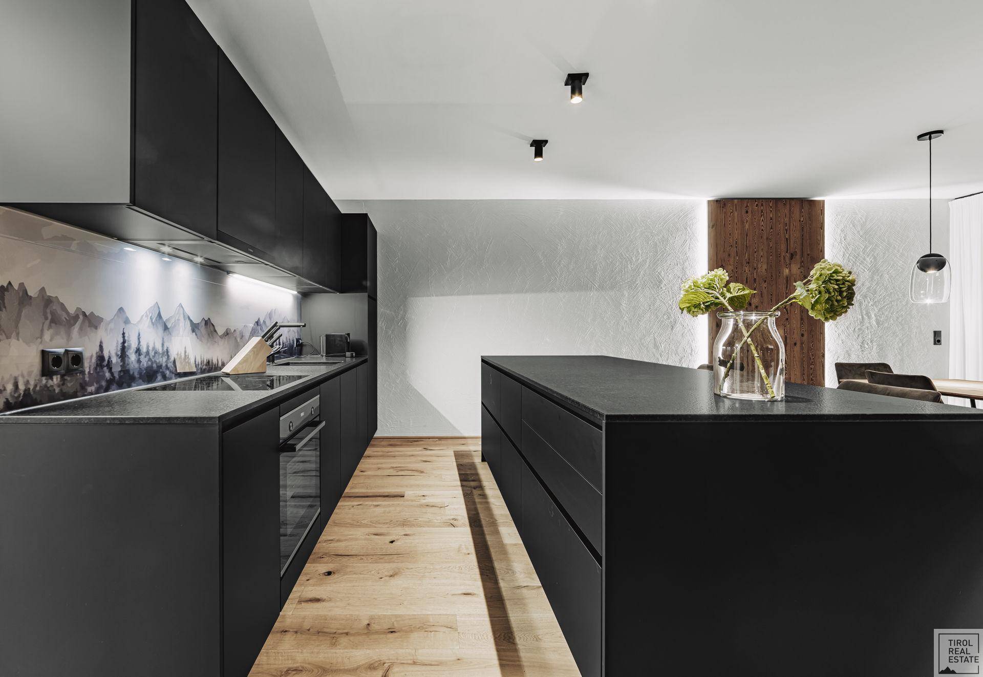 Elegante schwarze Küche mit integrierten Geräten, Kochinsel und moderner Rückwand.