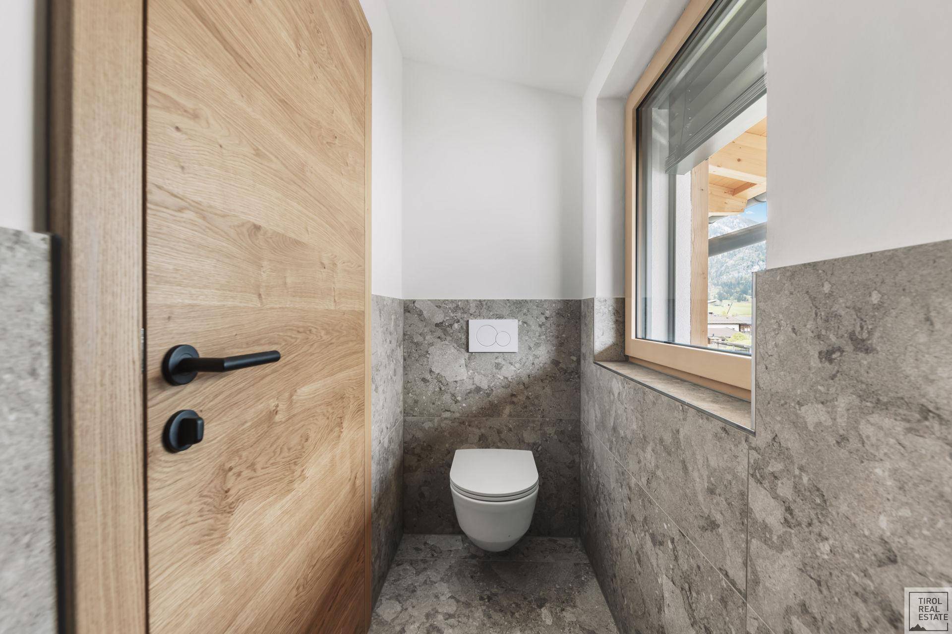 Modernes Gäste-WC mit Wand-WC und Fenster für natürliche Belüftung und Licht.
