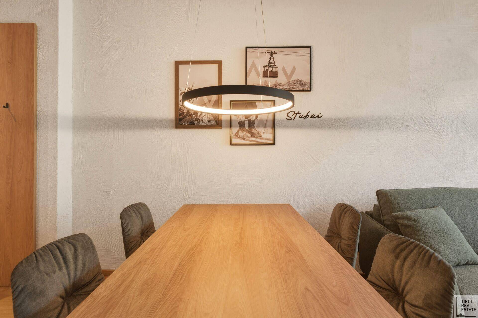 Essbereich mit modernem Holztisch und bequemen Stühlen unter einer Designerlampe.