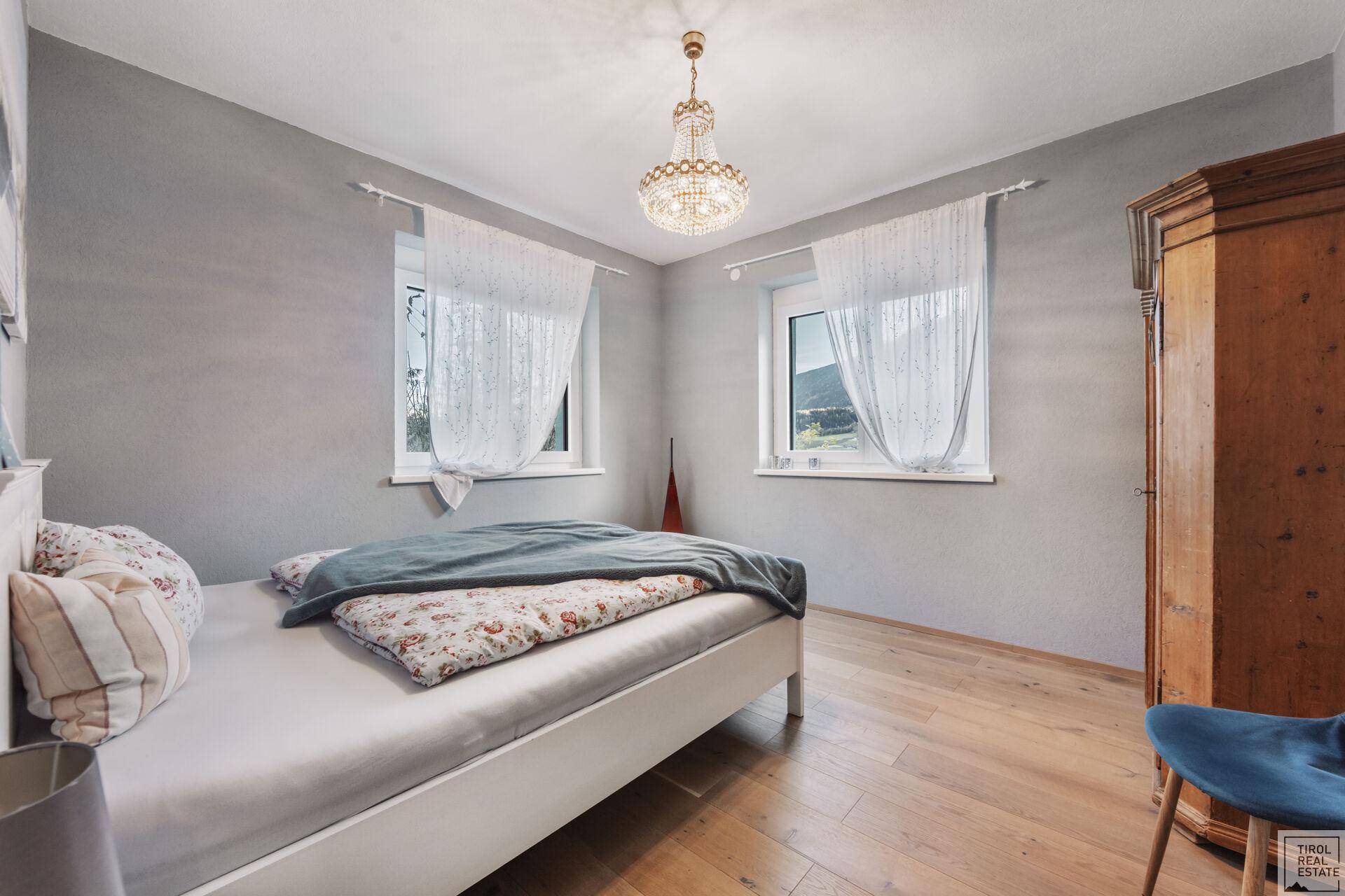 Helles Schlafzimmer mit Holzboden, Kleiderschrank und Bergblick.