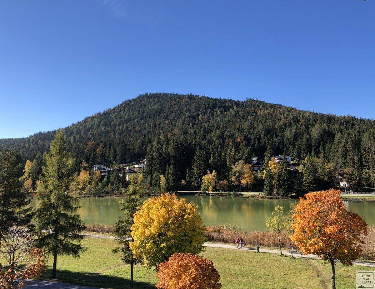 Malerischer Blick auf einen See und bewaldete Berge unter blauem Himmel.