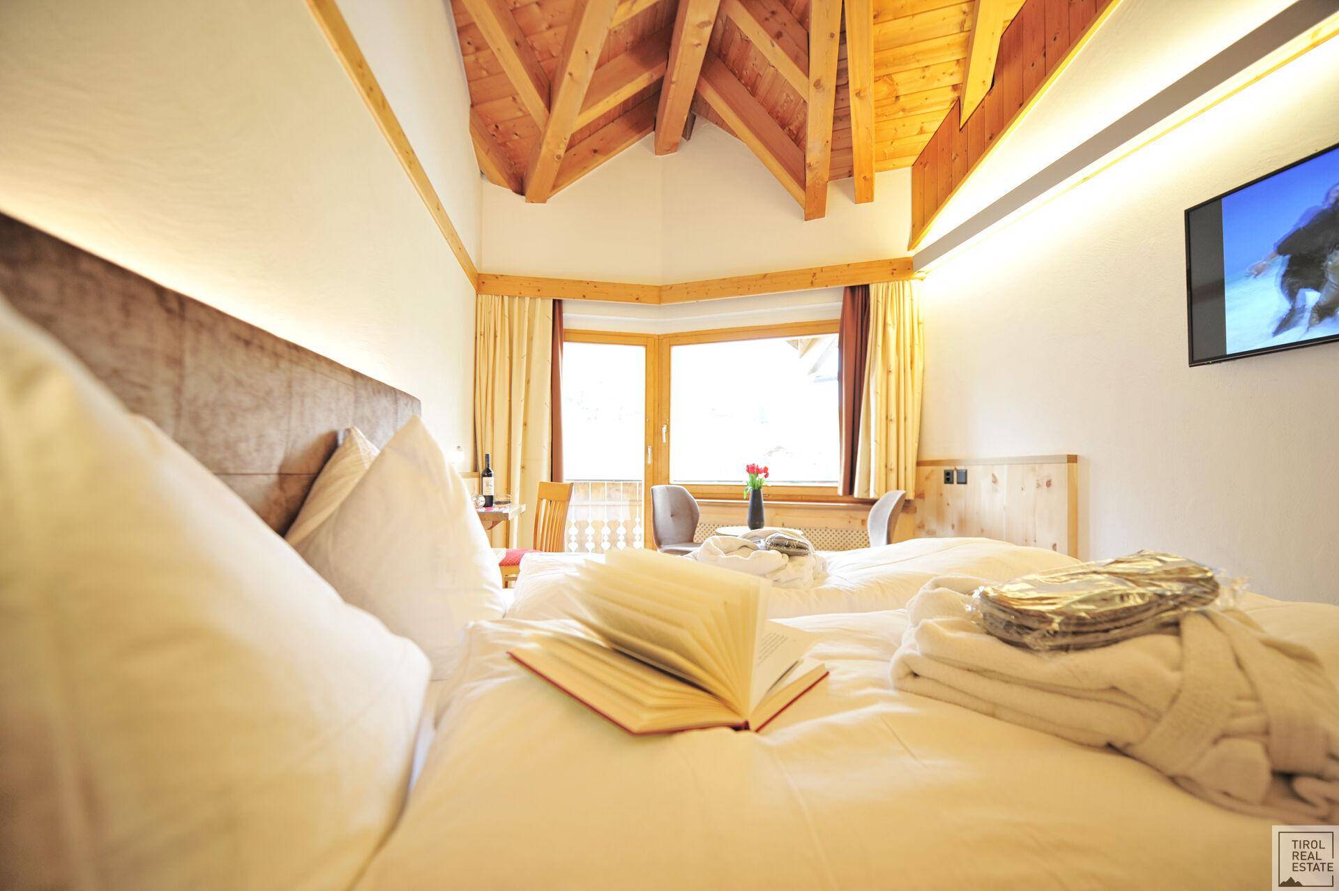 Nahaufnahme des Bettes in einem Schlafzimmer mit Holzbalkendecke und Blick nach draußen.