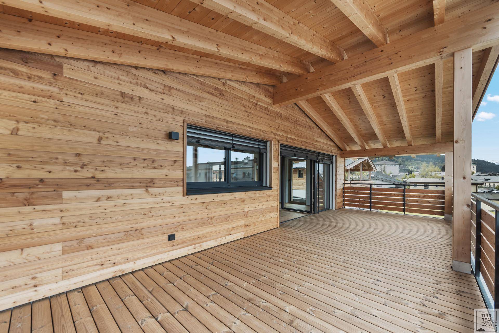 Breite Holzterrasse mit Holzwänden und Blick auf die Umgebung, perfekt für Outdoor-Living.