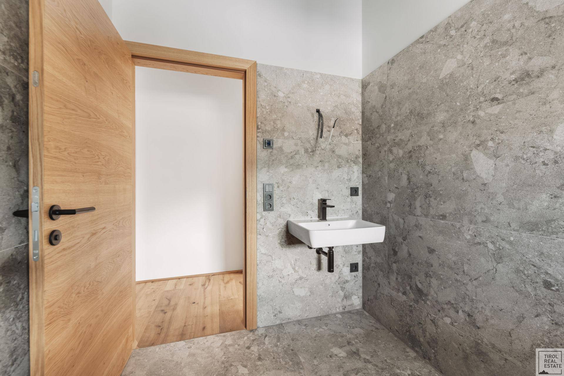 Kleines Gäste-WC mit modernem Waschbecken und grauen Fliesen an den Wänden.