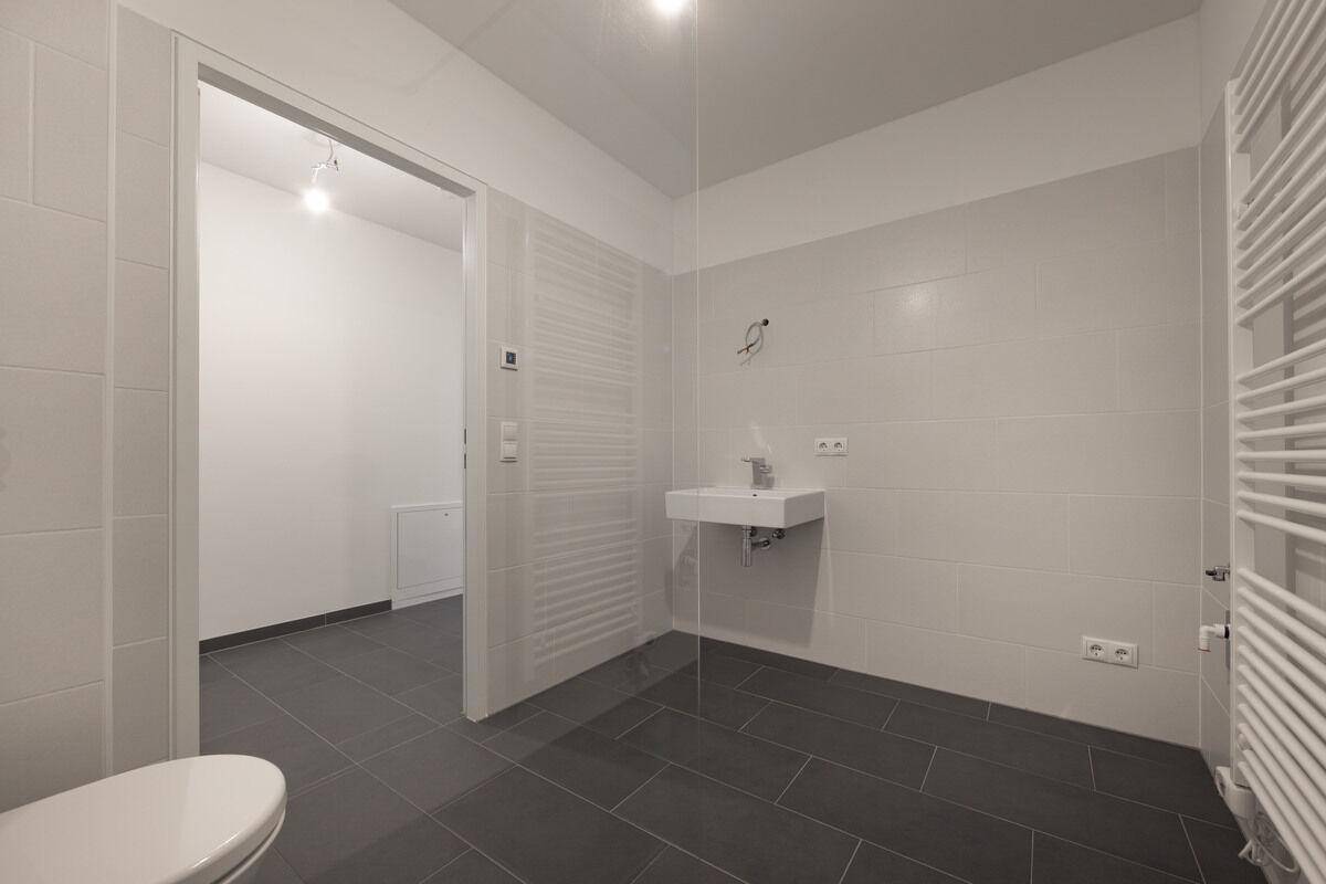 Helles Badezimmer mit modernem Design, Dusche, Waschbecken und beheiztem Handtuchhalter.