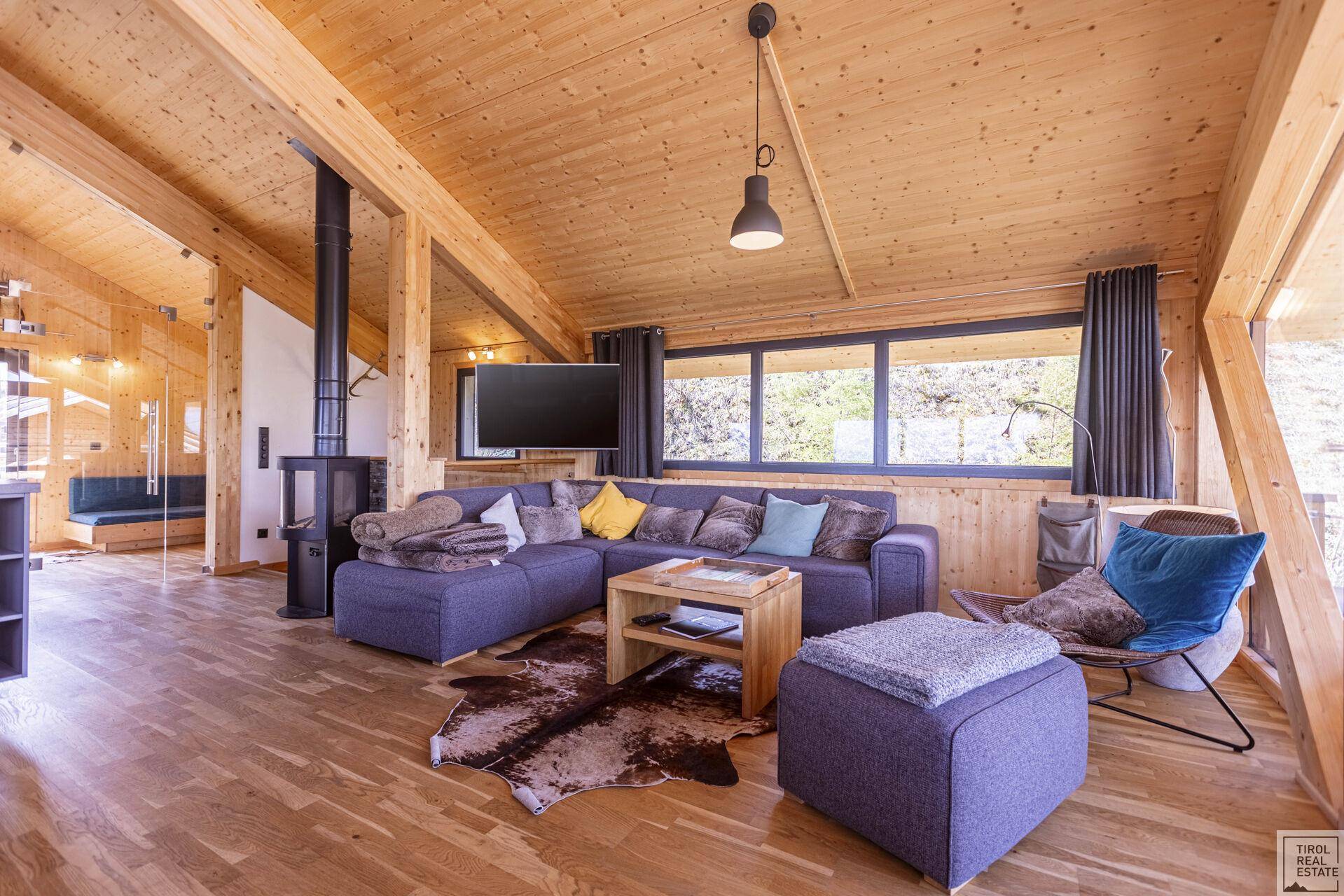 Heller Wohnbereich mit gemütlichem Sofa, Kaminofen und Holzeinrichtung.
