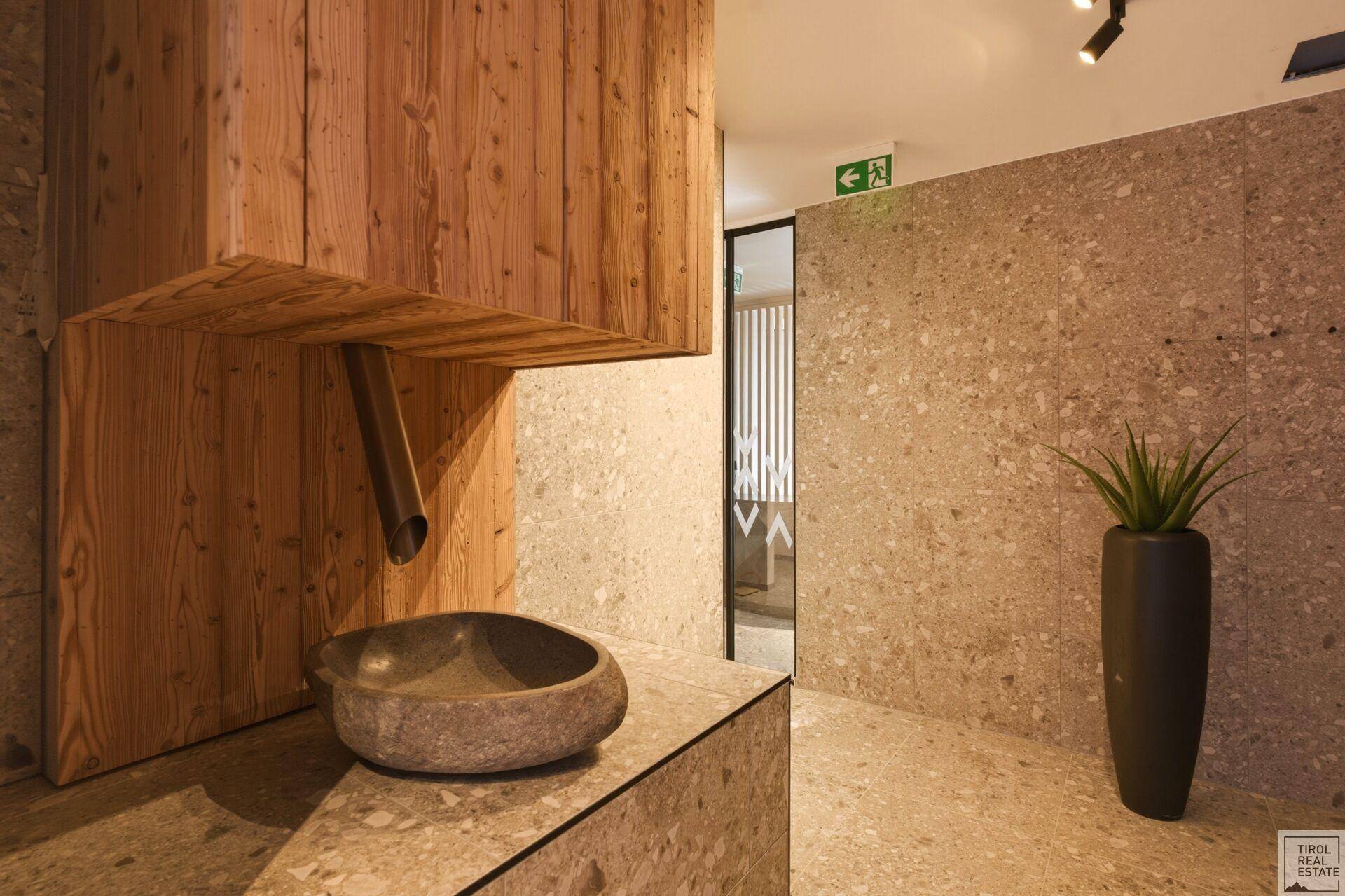 Waschbecken aus Stein in einem modernen Wellnessbereich mit Holzelementen.