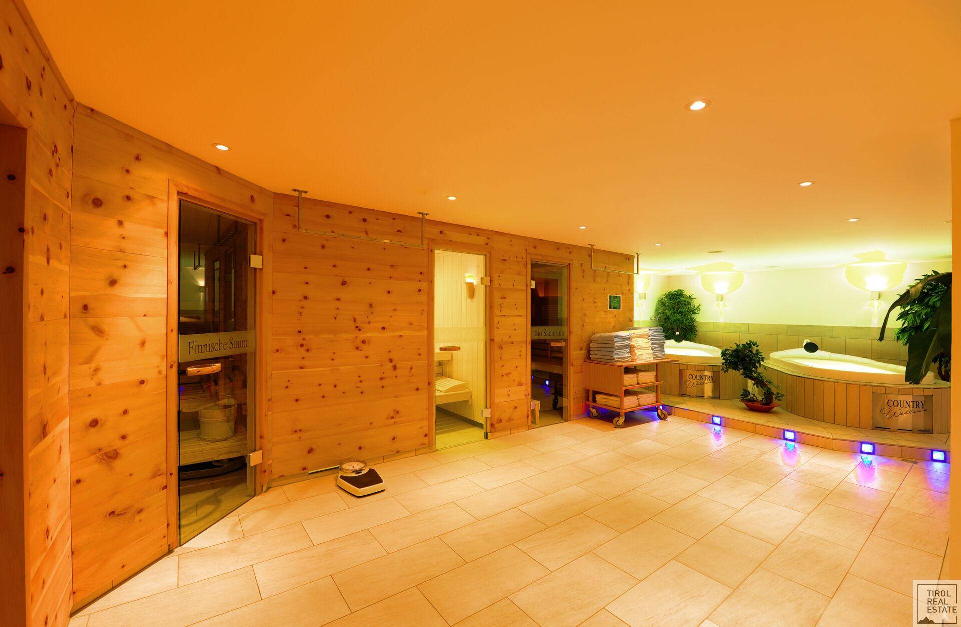 Wellnessbereich mit zwei Whirlpools, Holzvertäfelung und indirekter Beleuchtung für eine entspannende Atmosphäre.