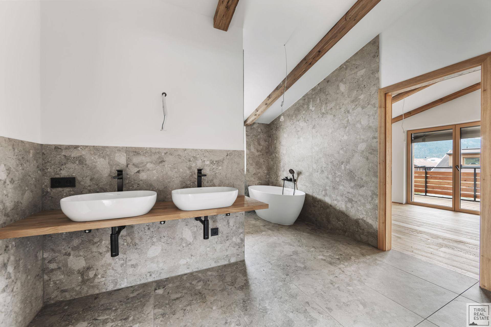 Modernes Badezimmer mit Doppelwaschbecken, freistehender Badewanne und Fliesenboden.