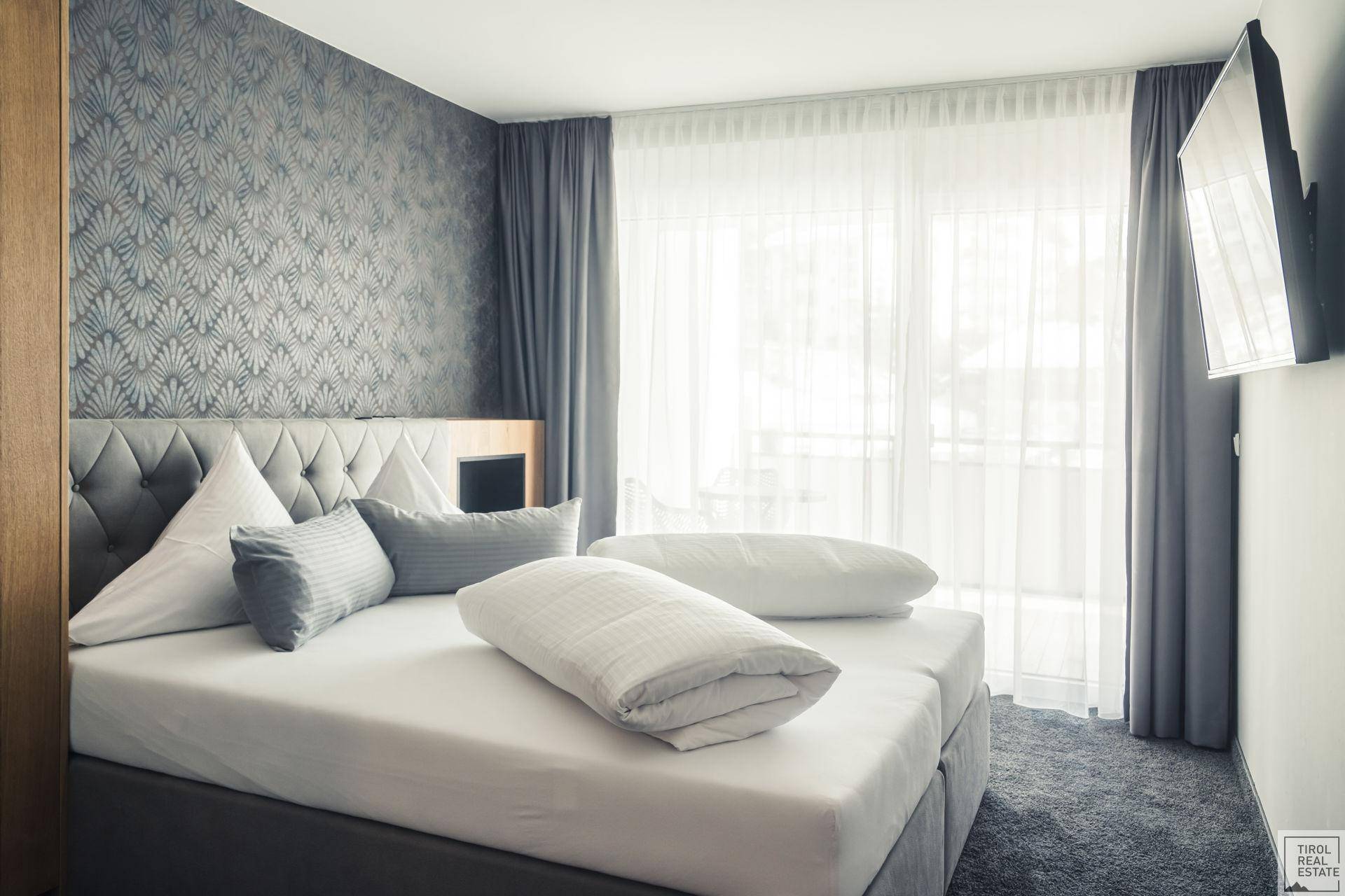 Gemütliches Schlafzimmer mit großem Bett, dekorativer Tapete und Zugang zum Balkon.