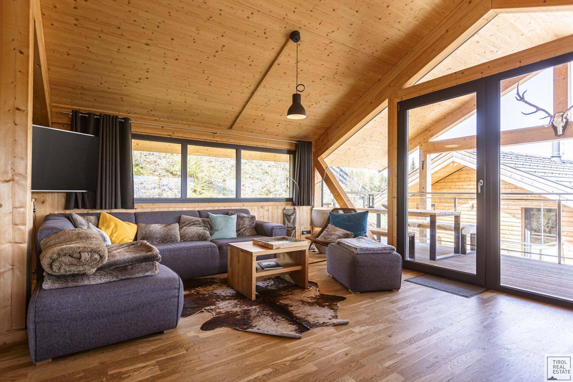 Geräumiger Wohnbereich mit großem Sofa, Holzboden und Zugang zur Terrasse.