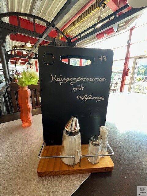 Nahaufnahme einer Menütafel auf einem Holztisch im Restaurantbereich mit Salz- und Pfefferstreuern.
