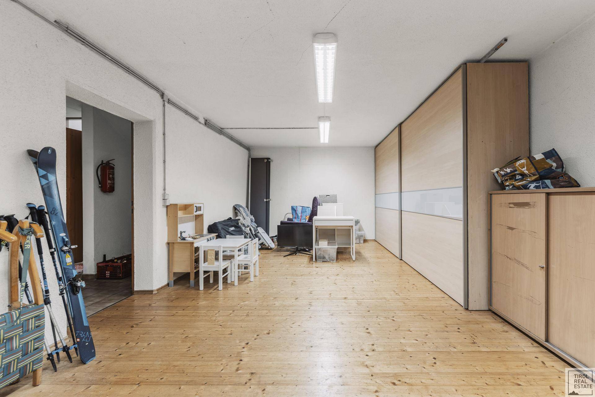 Großer Abstellraum im Keller mit Holzfußboden und praktischen Einbauschränken.
