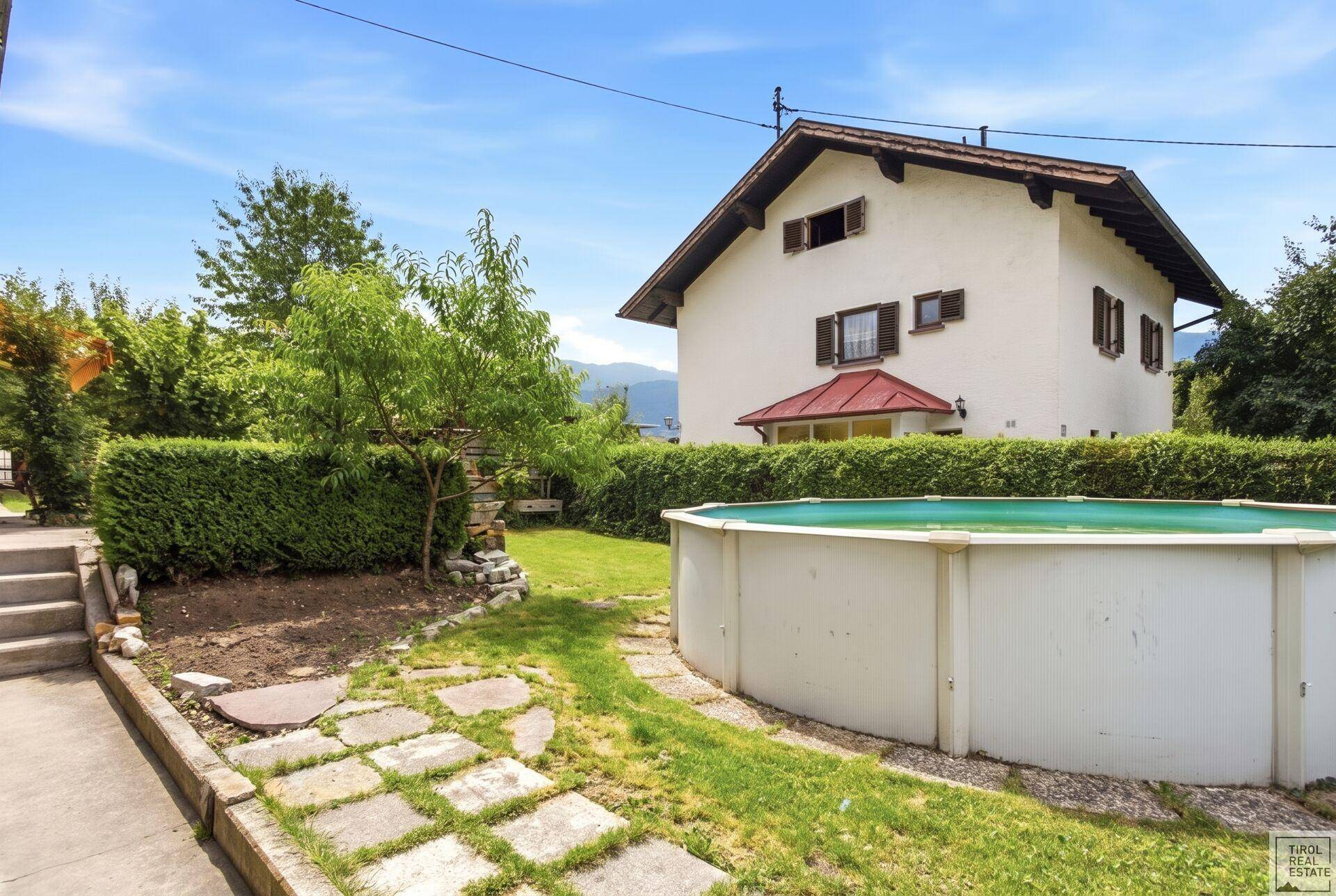 Gepflegter Gartenbereich mit Aufstellpool, Rasenfläche und Hecken.