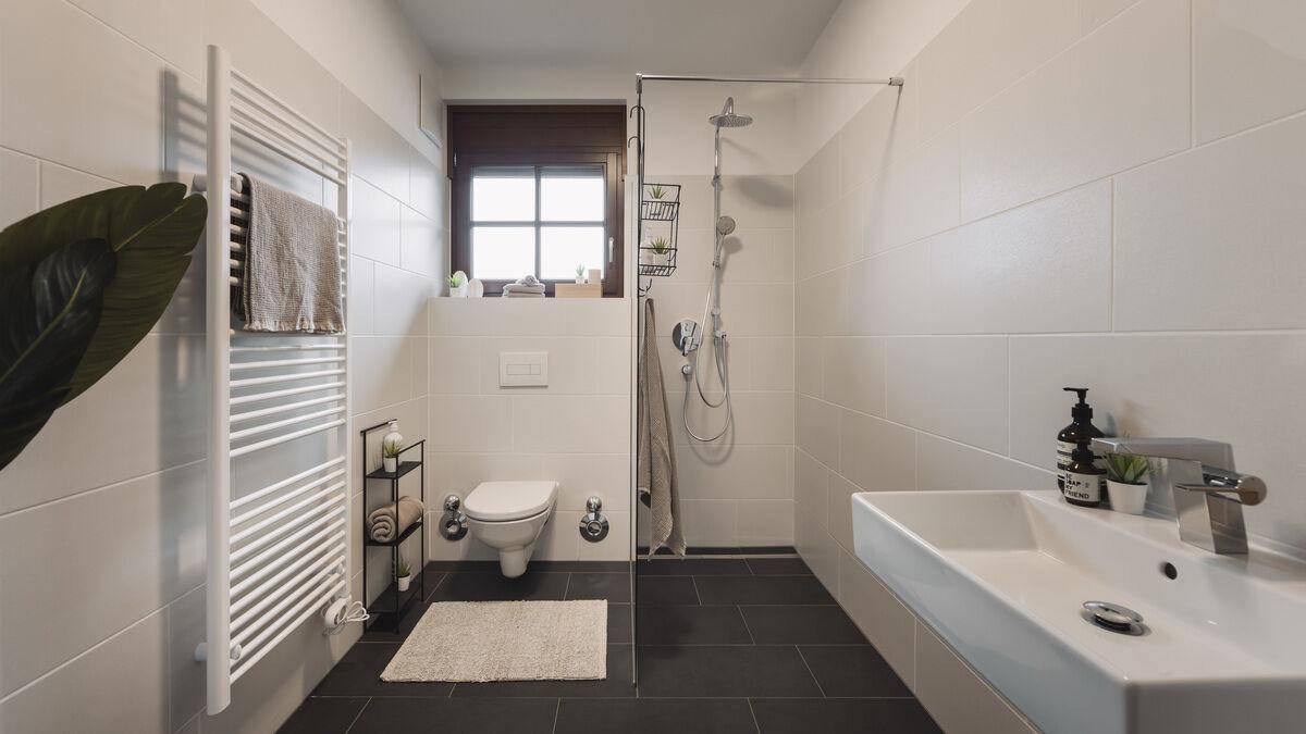 Modernes Badezimmer mit großer Dusche, Wand-WC und beheiztem Handtuchhalter.