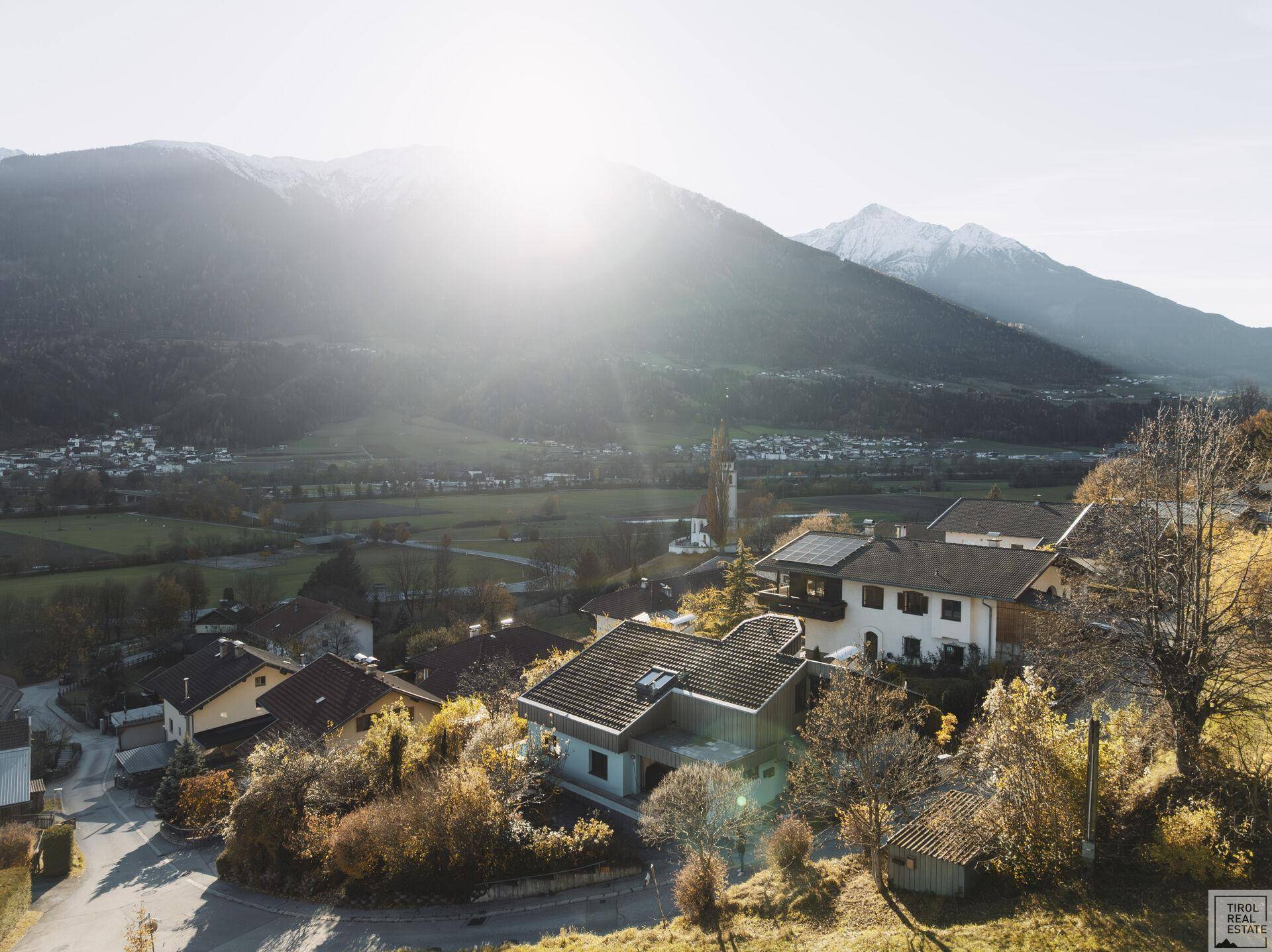 Panoramablick auf die umliegende Berglandschaft und die Siedlung bei Sonnenlicht.