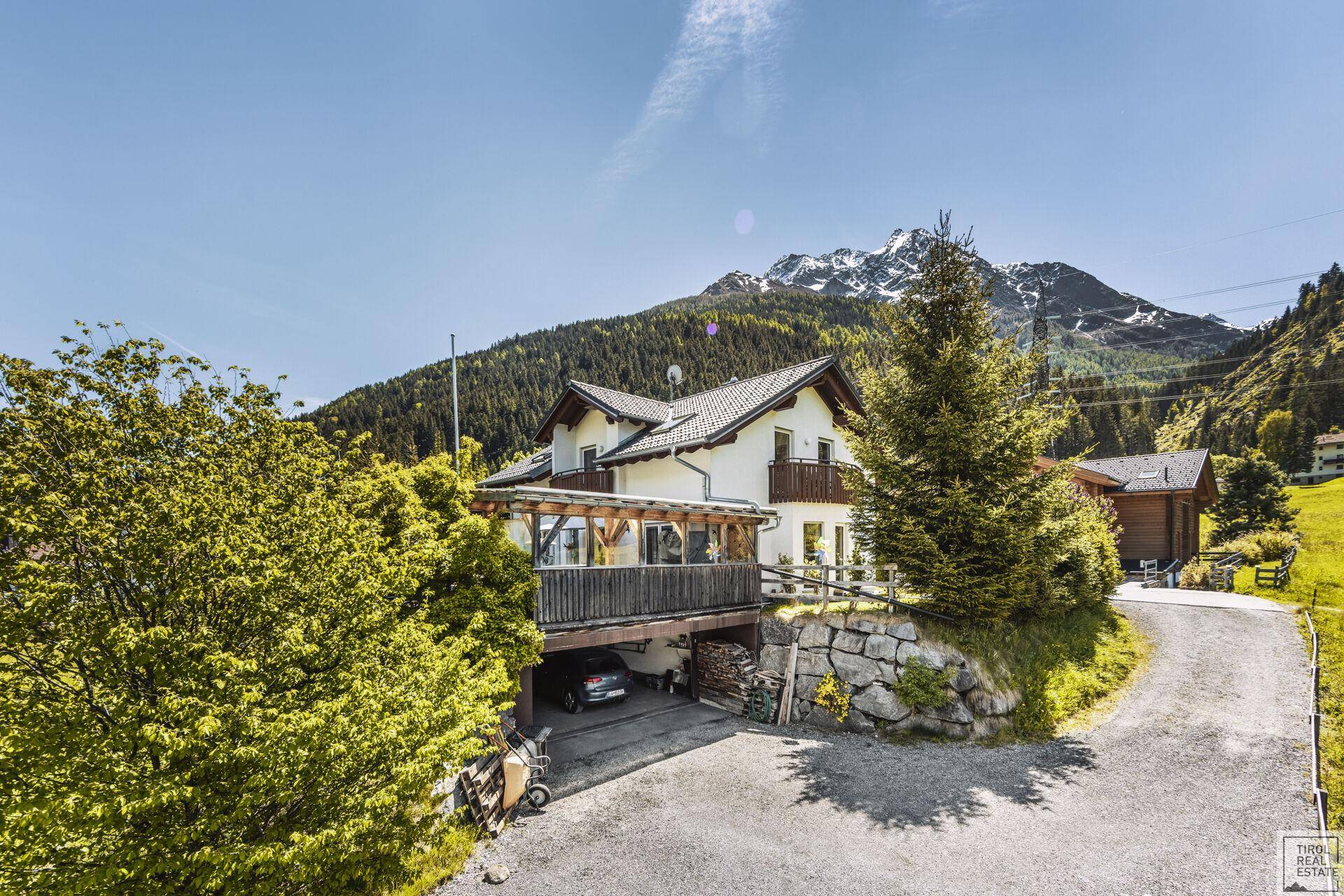 Charmantes Haus in alpiner Umgebung mit Carport, Auffahrt und beeindruckendem Bergpanorama.