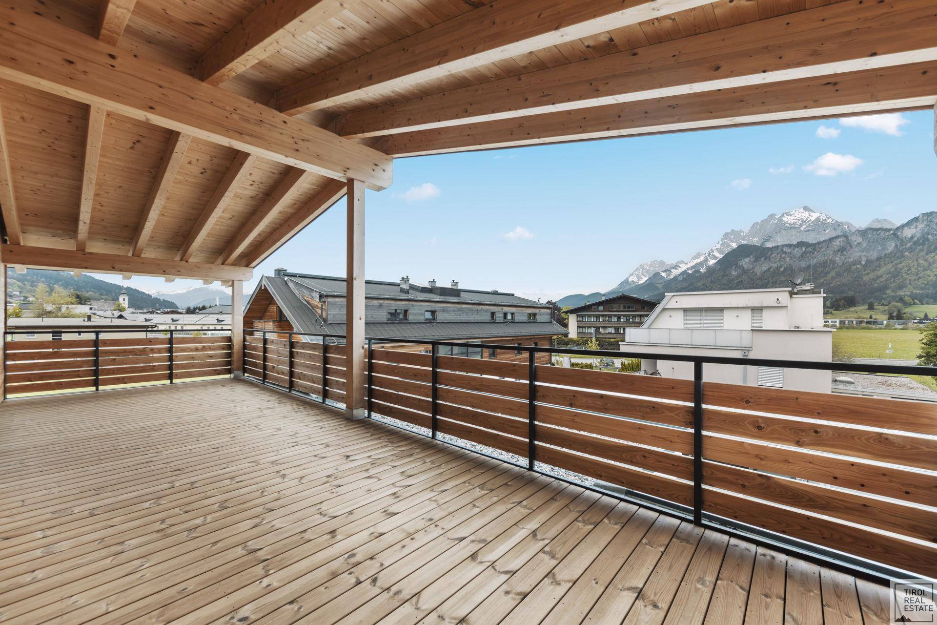 Geräumige Holzterrasse mit Bergblick und Holzbalkendecke, ideal für Entspannung im Freien.