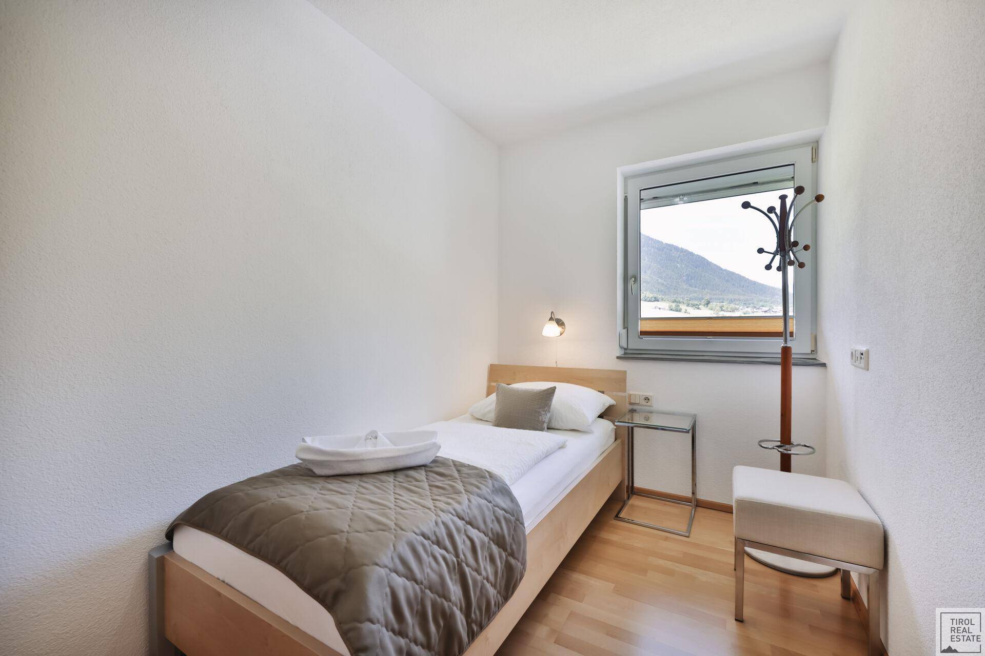 Kleines Schlafzimmer mit Einzelbett, Holzboden und Fenster mit Bergblick.