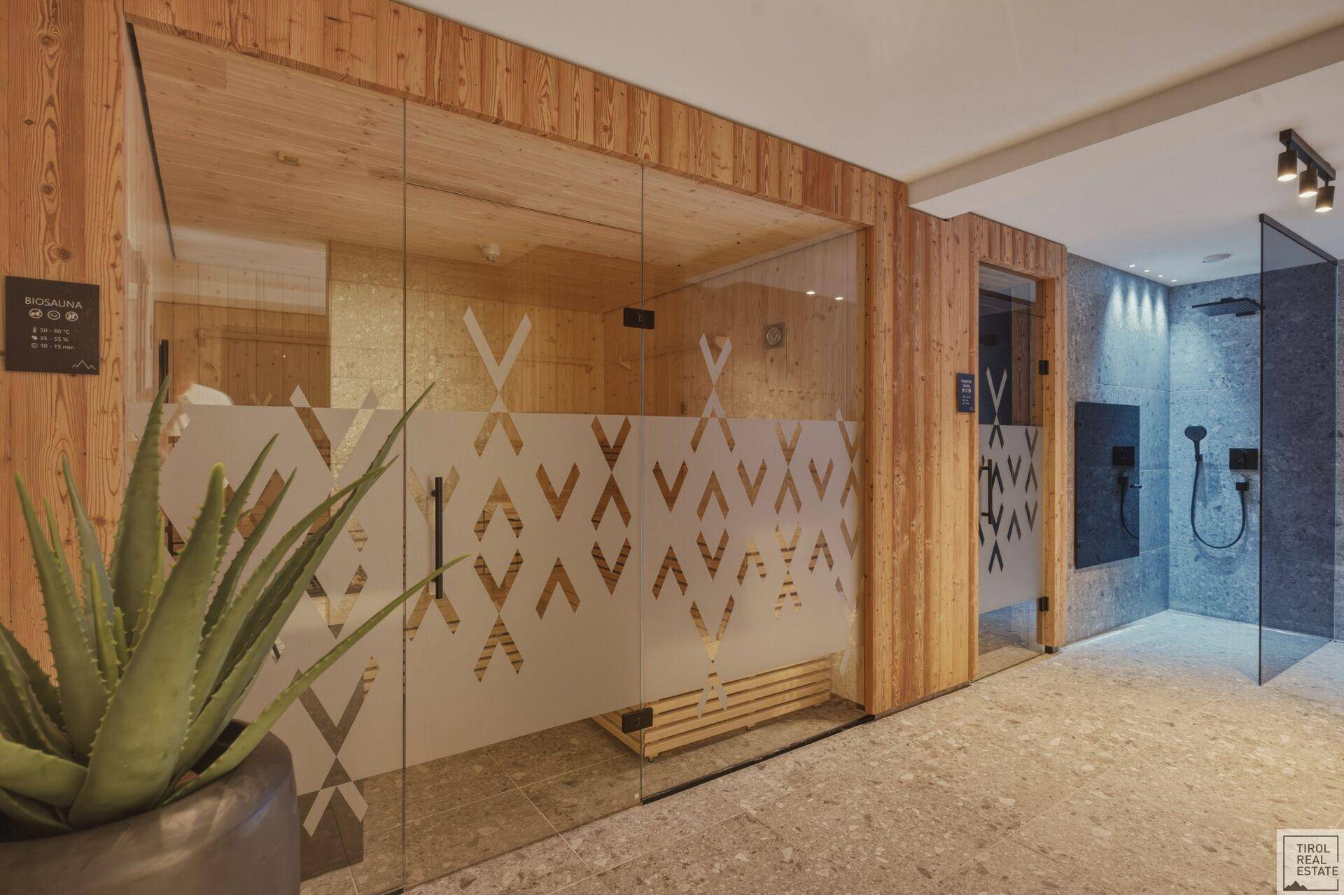Exklusiver Wellnessbereich mit Sauna, modernen Duschen und dekorativer Pflanze.