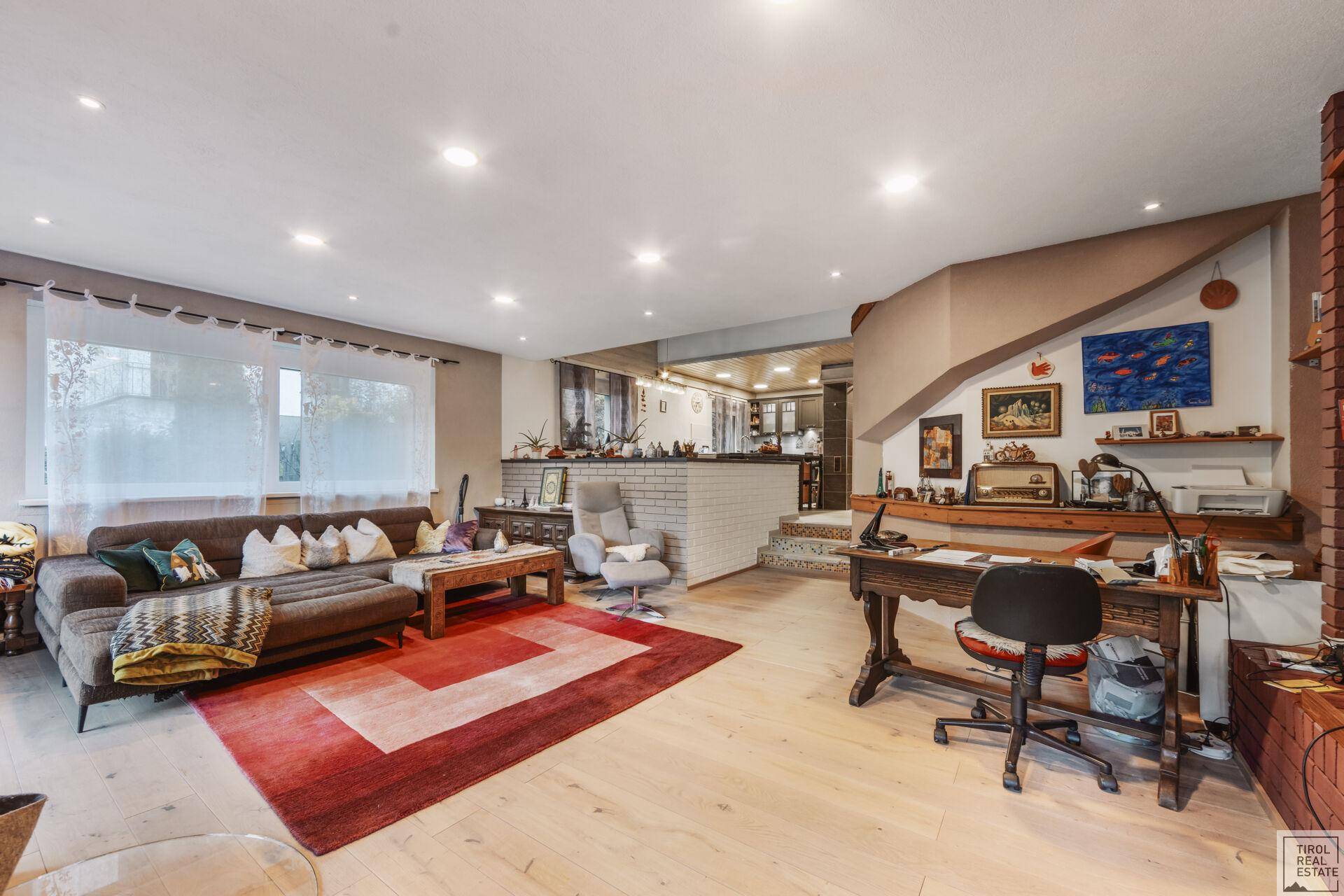 Heller Wohnbereich mit Holzboden, großem Sofa und integriertem Arbeitsplatz.