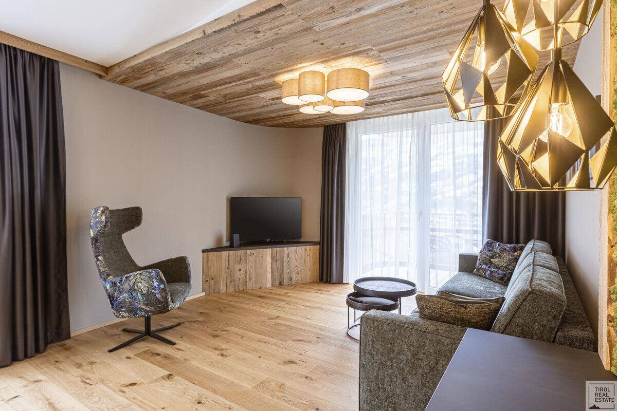 Modern eingerichtetes Wohnzimmer mit Holzboden, Fernseher und bequemen Sitzmöbeln.