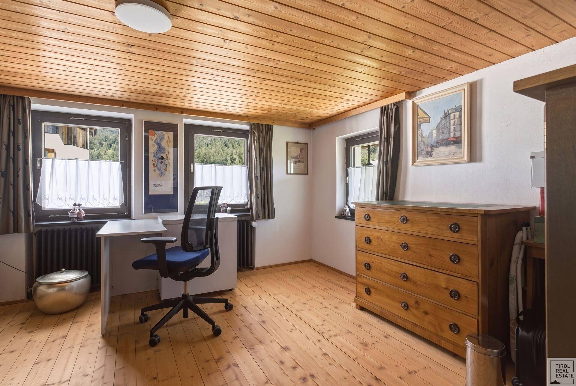 Helles Büro mit Holzdielenboden, Holzdecke und Blick ins Grüne.