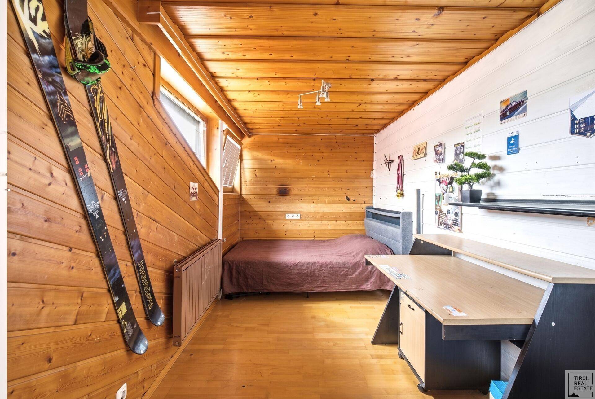 Rustikales Schlafzimmer mit Holztäfelung, Schreibtisch und Dachschräge.