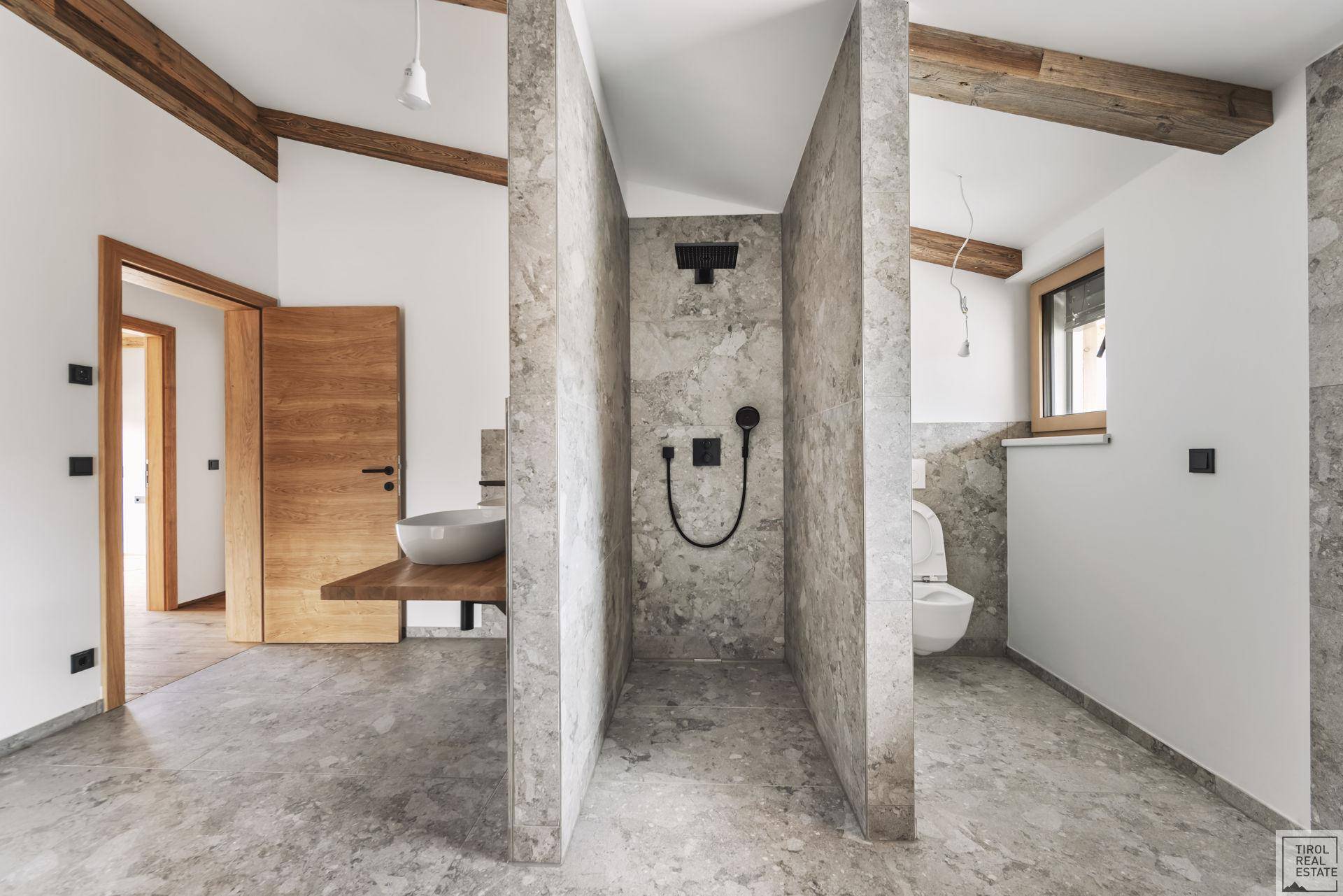 Modernes Badezimmer mit begehbarer Dusche, Wand-WC und eleganten grauen Fliesen.
