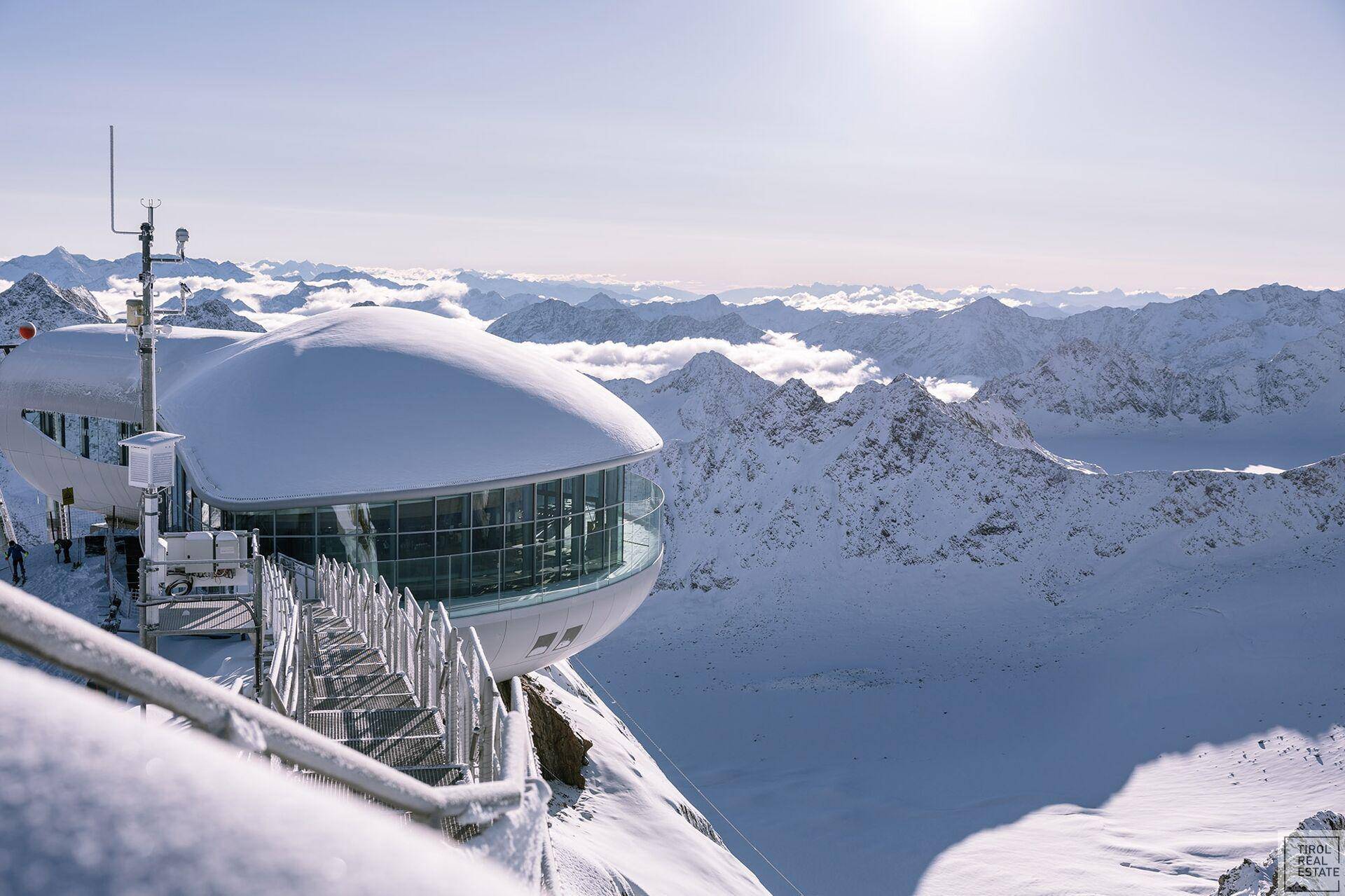 Modernes Gebäude auf einem schneebedeckten Berggipfel mit Panoramablick.
