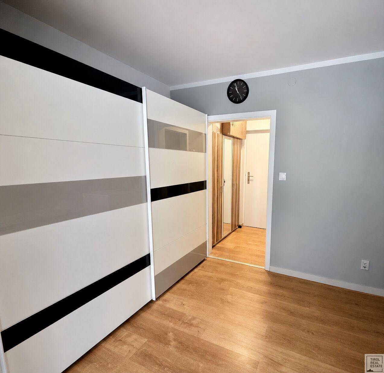 Schlafzimmer mit hellem Holzboden und großem Schiebetürenschrank.