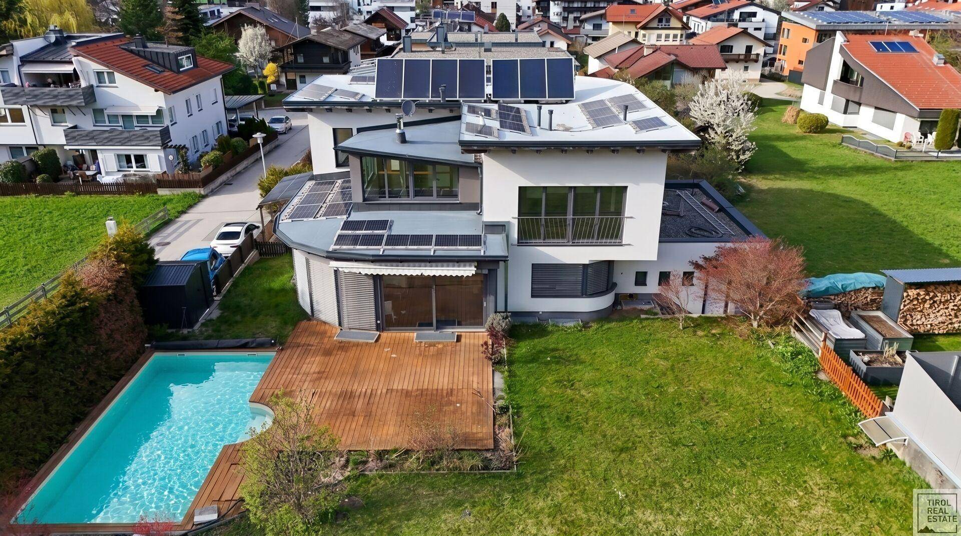 Luftaufnahme des Hauses mit Pool, Holzterrasse und Photovoltaikanlage auf dem Dach, umgeben von Natur.