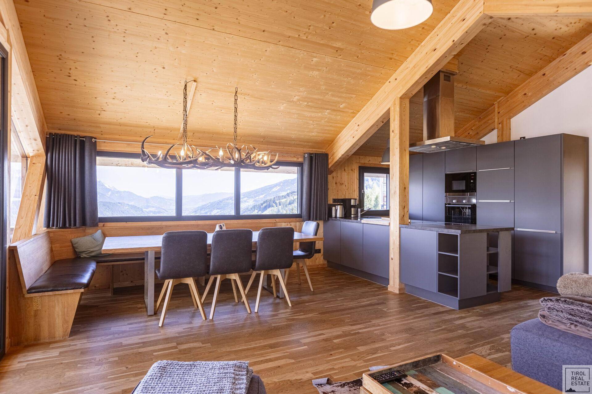 Offener Wohn-Essbereich mit moderner Küche, Holzelementen und Bergblick.