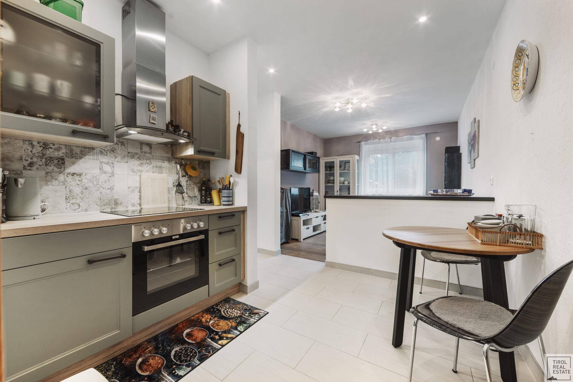 Kompakte Küche mit Essbereich, modernen Geräten und hellem Fliesenboden.