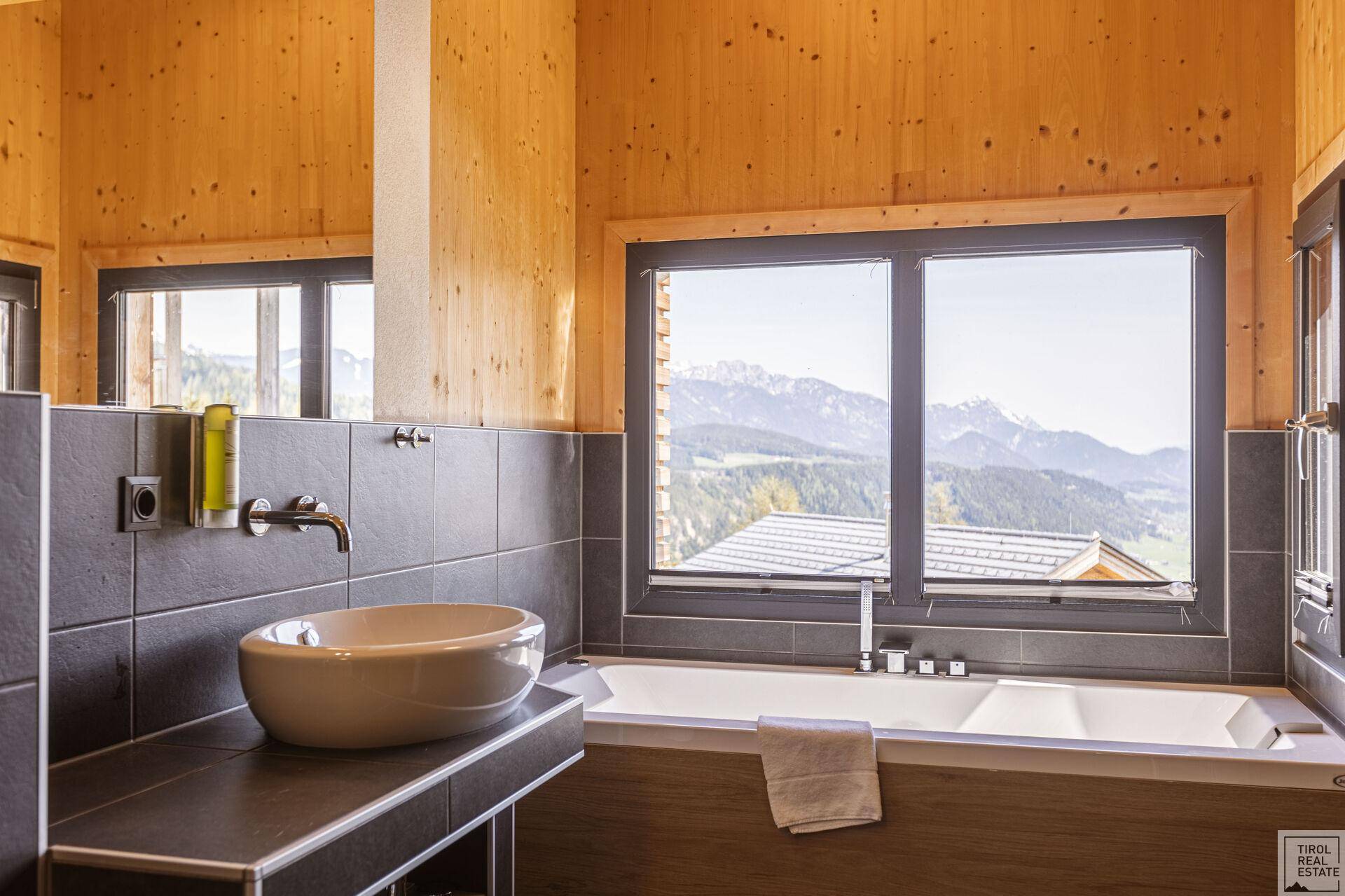 Modernes Badezimmer mit Badewanne, Aufsatzwaschbecken und Bergblick.