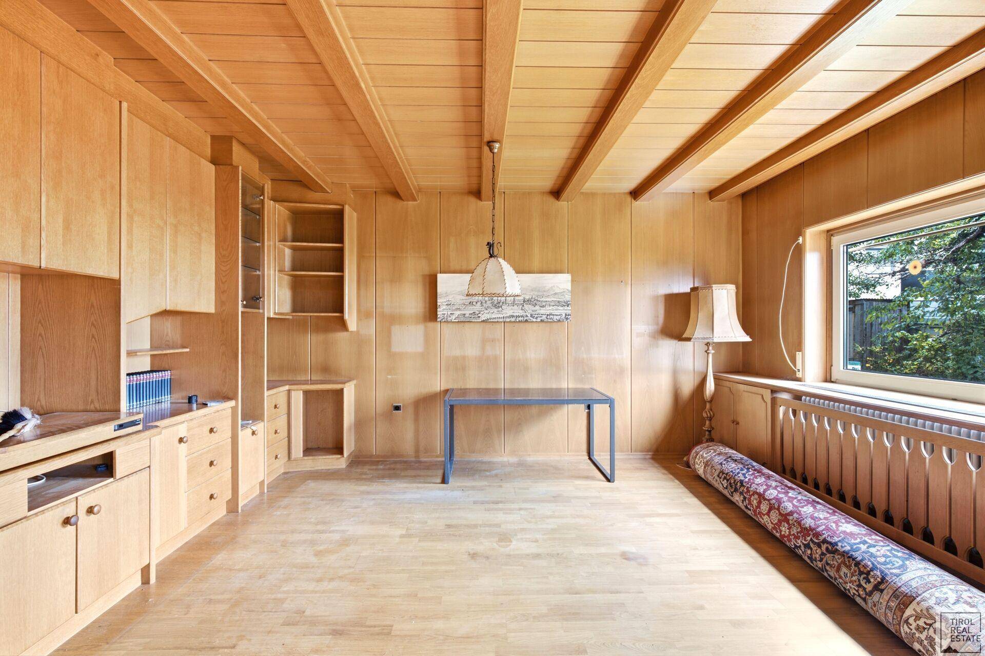Geräumiger Wohn-Essbereich mit Holzvertäfelung, Holzbalkendecke und Parkettboden.