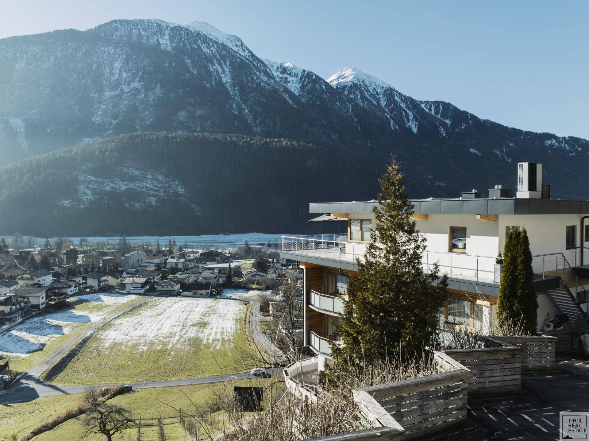 Modernes Gebäude in alpiner Landschaft mit schneebedeckten Bergen im Hintergrund.