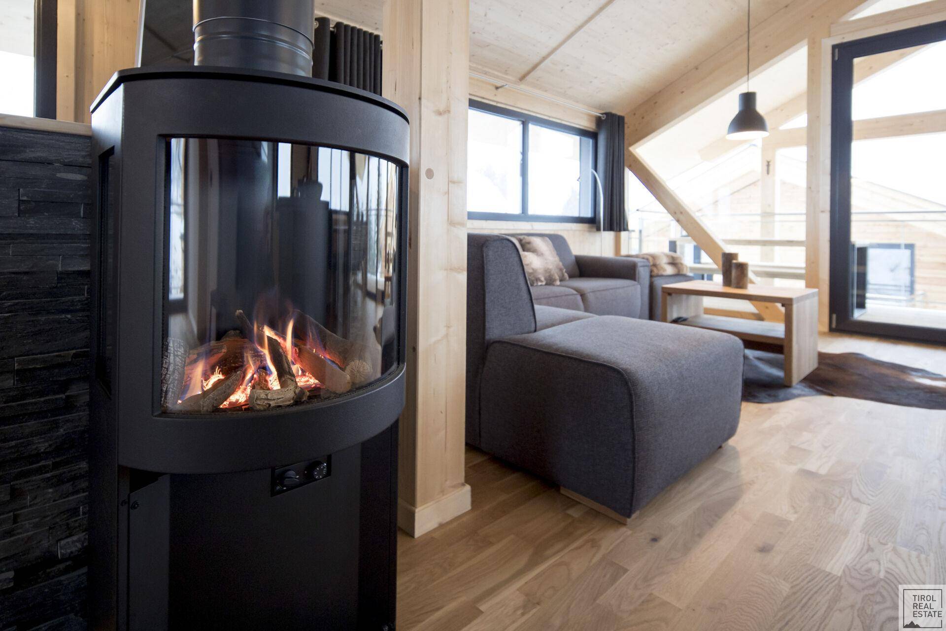 Moderner Kaminofen im Wohnbereich mit Holzboden und gemütlichem Sofa.