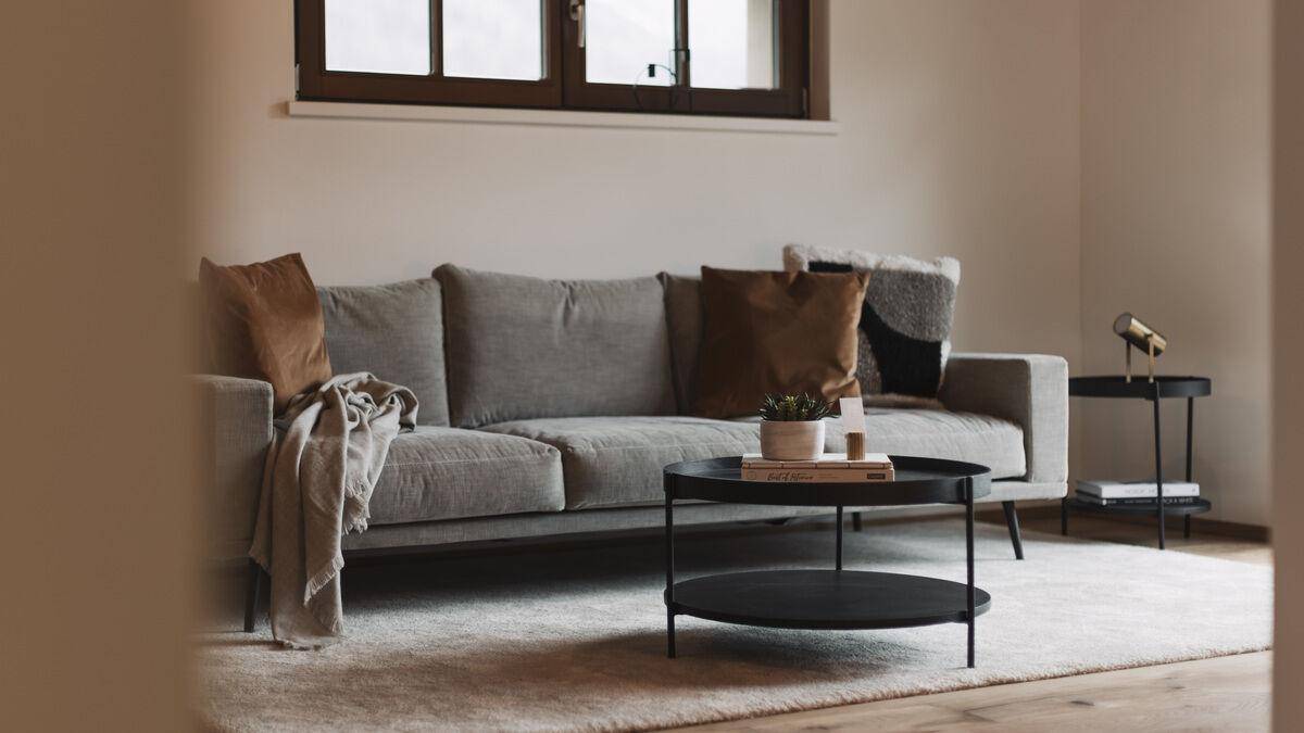 Detailansicht eines modernen Wohnzimmers mit grauem Sofa und rundem Couchtisch.