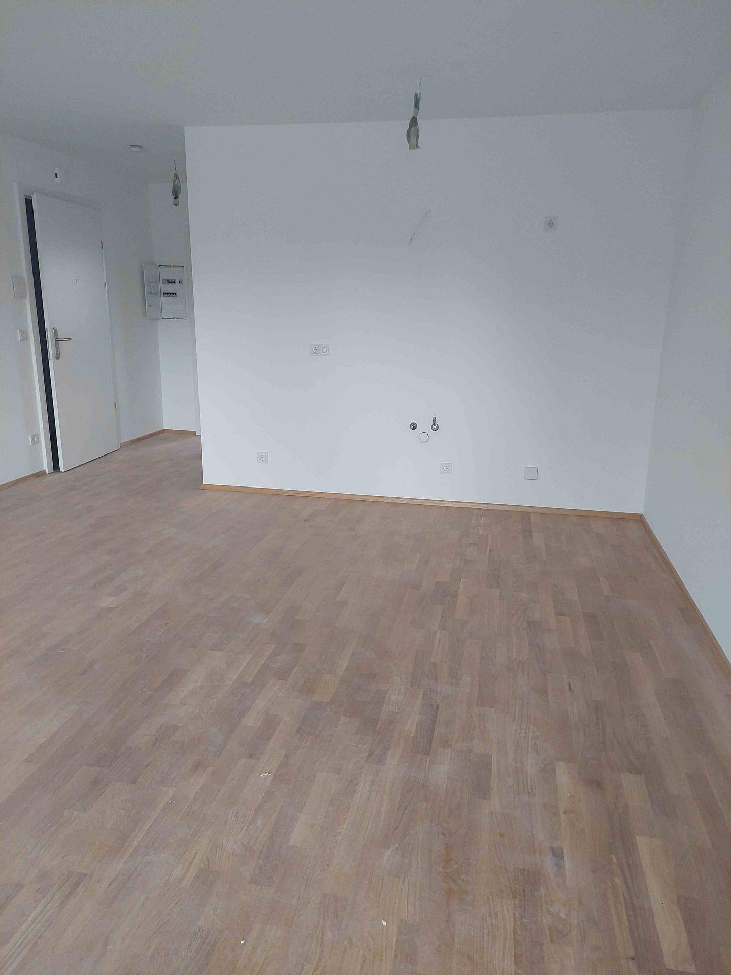 Heller, leerer Raum mit neuem Holzplankenboden und weißen Wänden, bereit für die Einrichtung.