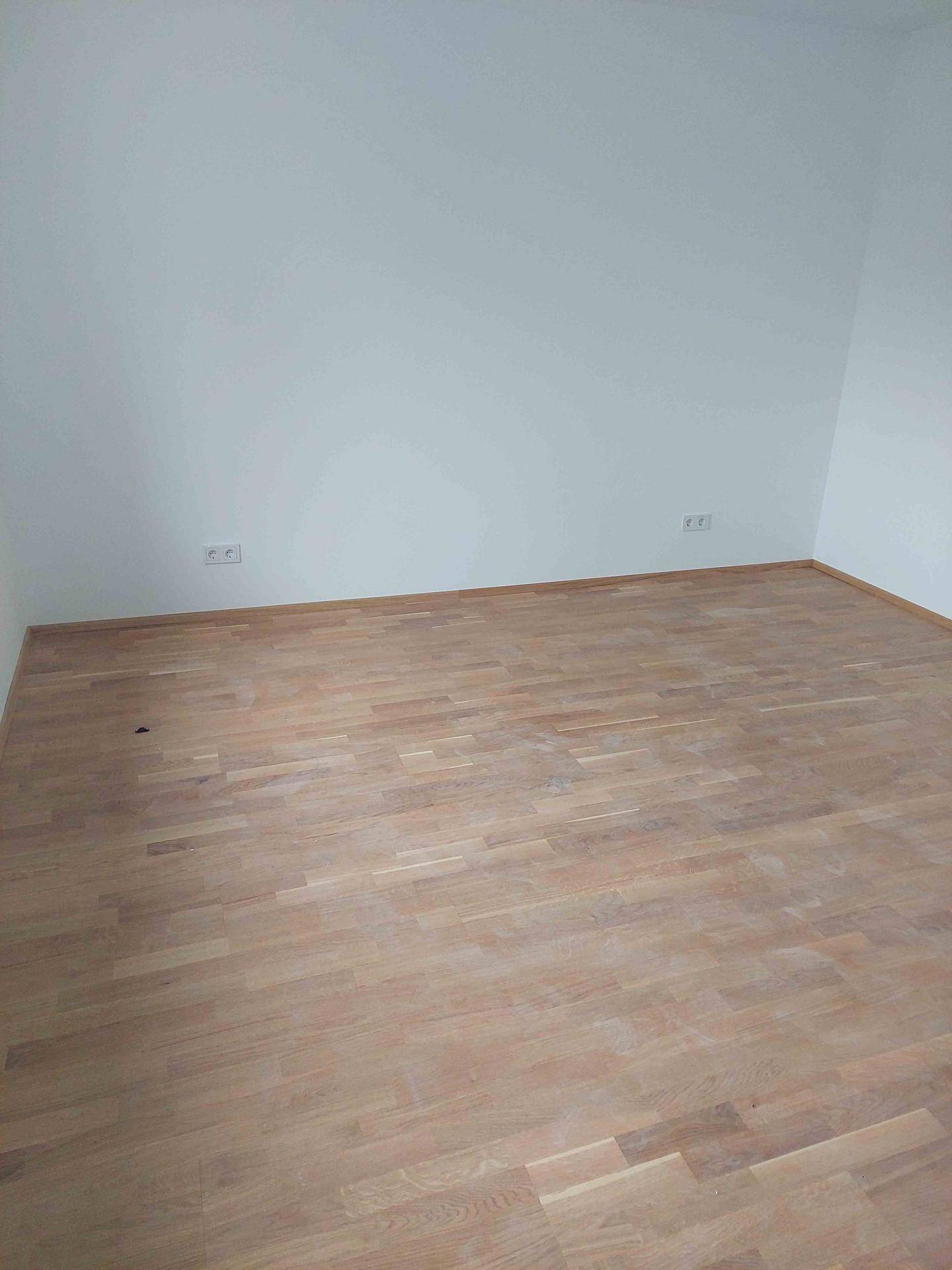 Leerer Raum mit hellem Holzplankenboden und sauberen weißen Wänden, ideal für ein Schlafzimmer.