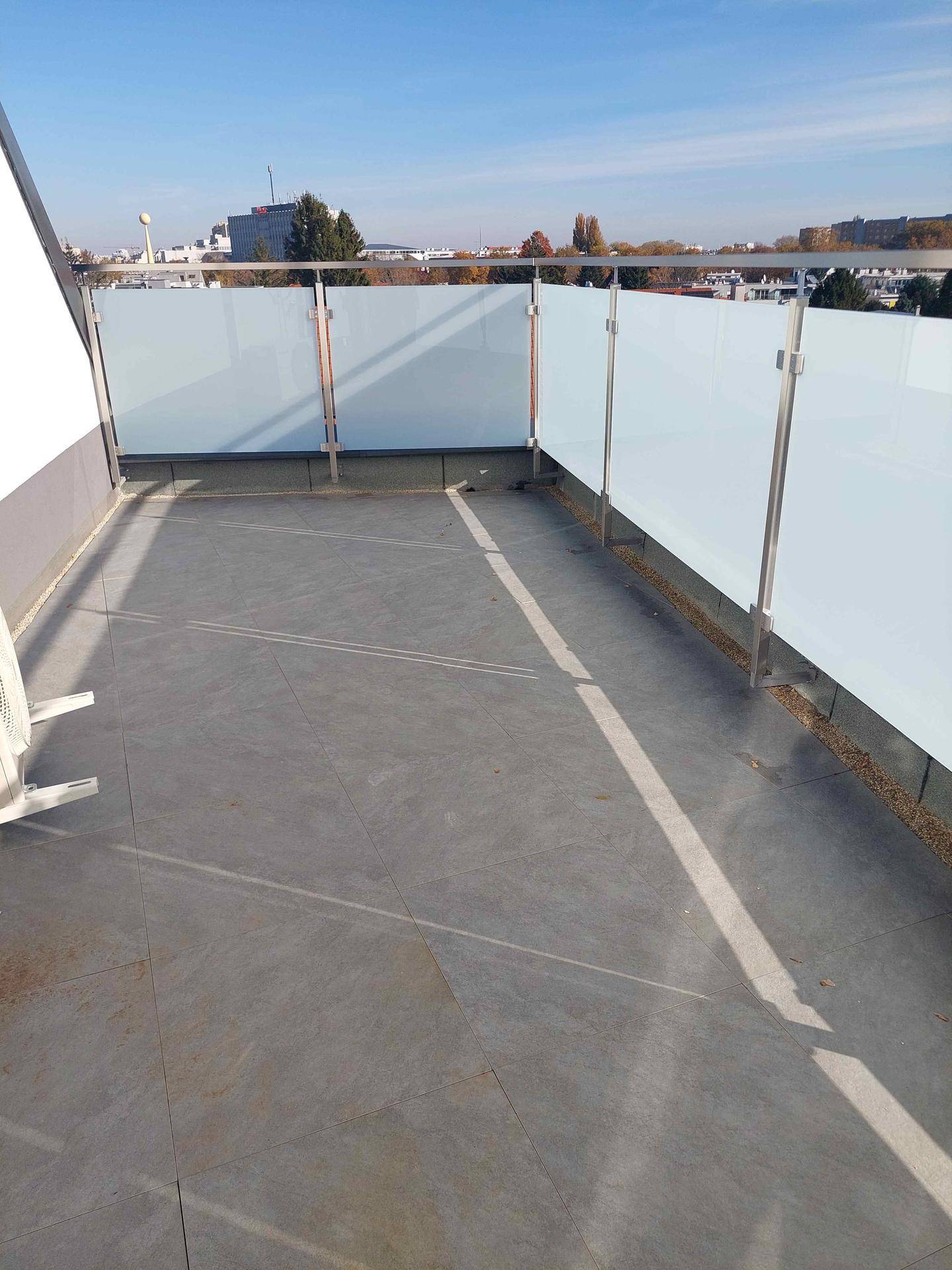 Geräumige Terrasse mit modernen Fliesen und Milchglasgeländer, inklusive Klimaanlagen-Außeneinheit.