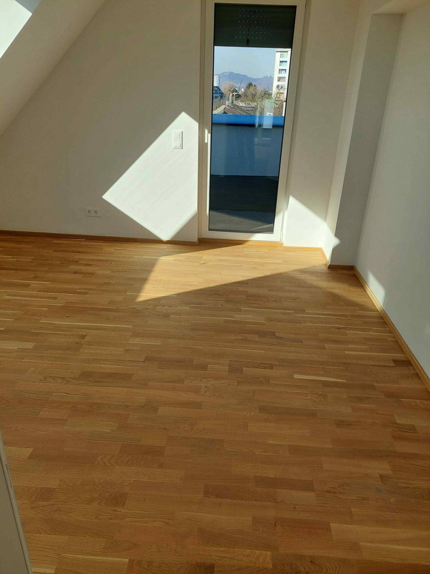 Sonniges Zimmer mit Holzboden und direktem Zugang zu einer Terrasse, ideal für frische Luft.