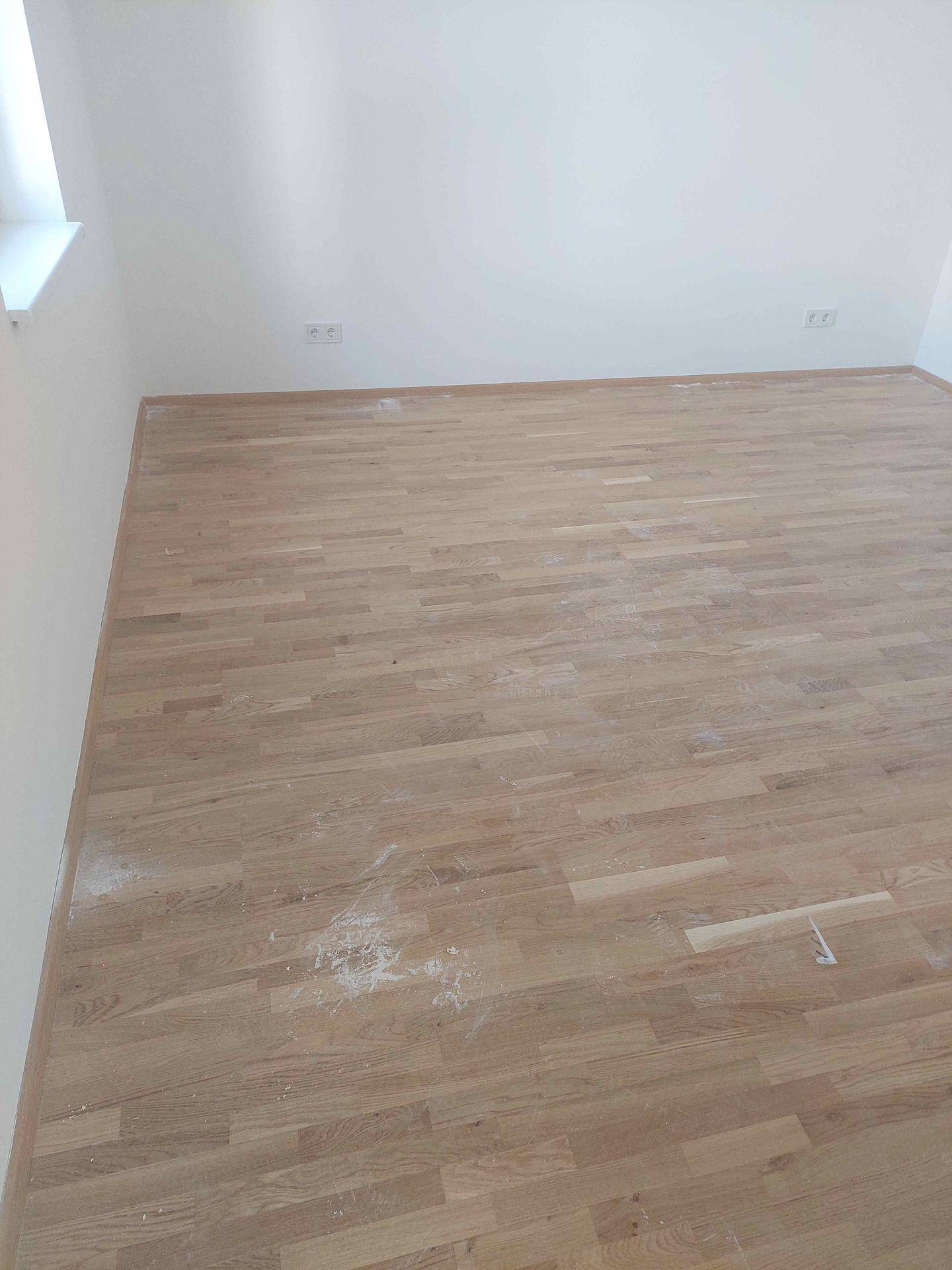 Geräumiger, heller Raum mit neuem Holzparkett und weißen Wänden, ideal für vielfältige Nutzung.