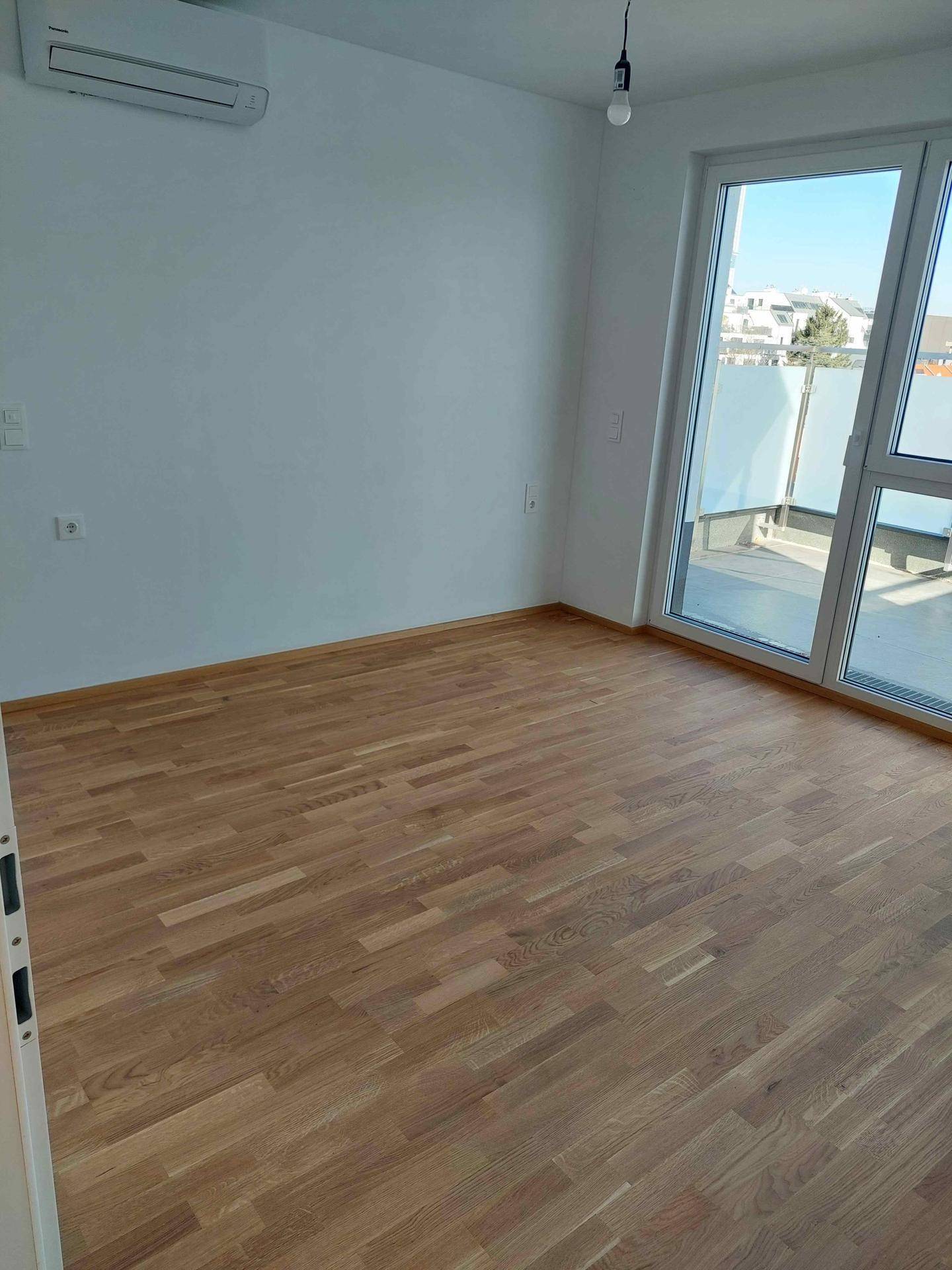 Schlafzimmer mit Holzboden, weiß gestrichenen Wänden und direktem Zugang zur sonnigen Terrasse.